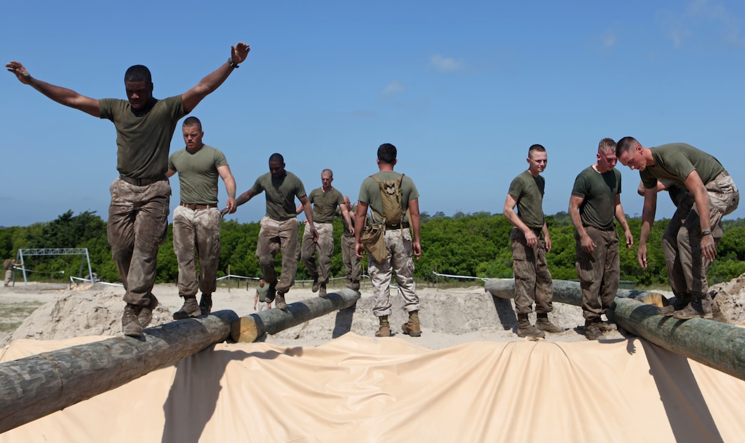Marines from 1st Battalion, 10th Marine Regiment (left), 2nd Marine Division, and Headquarters Battery, 10th Marine Regiment (right), cross an obstacle during the Engineer’s Challenge Obstacle course.  The event was part of the first 10th Marines’ Kings’ Games, a regiment-wide competition to build camaraderie throughout 10th Marines.  The team from 1st Bn., 10th Marines, defeated Headquarters Battery during the obstacle course.  (Official U.S. Marine Corps photo by Cpl. Tommy Bellegarde)