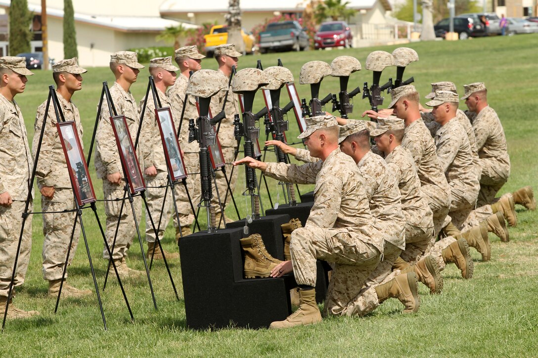 Marines with 3rd Battalion, 7th Marine Regiment hang dog tags from the battlefield crosses during the Remembrance Ceremony. Seven crosses were placed on the field to honor the Marines who were killed during combat operations in Afghanistan. (Official USMC photo by Lance Cpl. D.J. Wu)