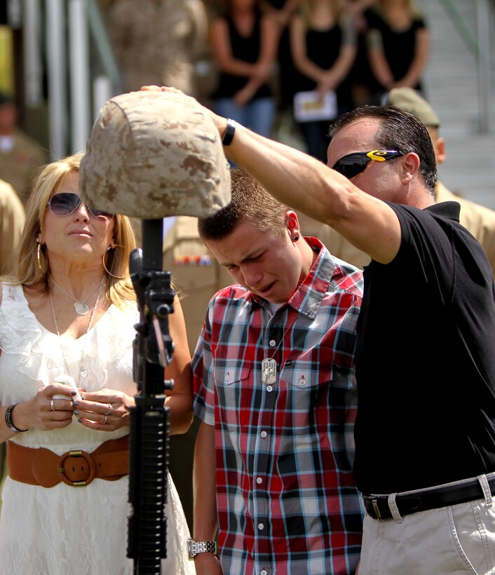 Denise Corral, mother of Lance Cpl. Joshua Corral, and his best friend, Tyler Hack, stand in front of the battlefield cross honoring Lance Cpl. Joshua Corral. Corral was one of seven Marines with 3rd Battalion, 7th Marine Regiment, who died while conducting combat operations during the unit’s last deployment to Afghanistan. (Official USMC photo by Diane Durden)