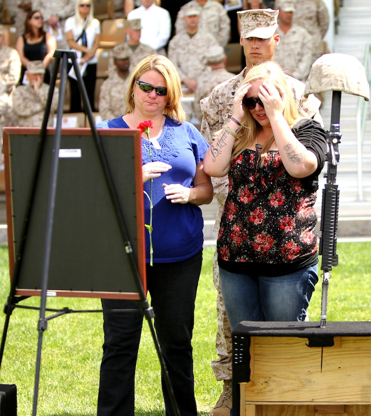 Marlene Shaw (left), mother of Cpl. Christopher Singer, and his wife, Brooke Singer, place a red carnation on the base of the battle field cross, honoring their loved on moments after the ceremony. (Official USMC photo by Diane Durden)