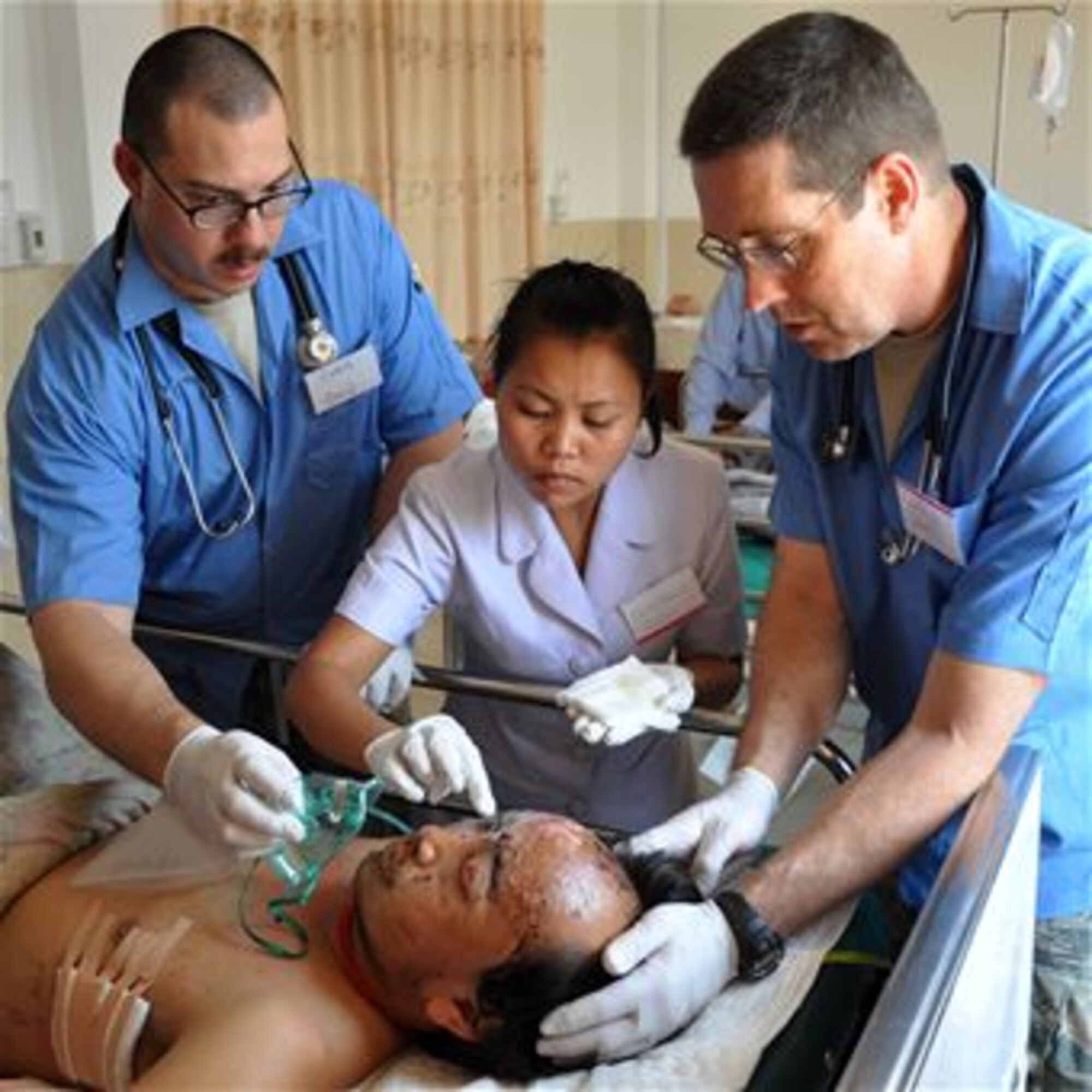Tech. Sgt. Christain Simpson, Lao nurse Syam Pone Ponsavah, and Lt. Col. David Worley apply antibiotic ointment to the wounds of Neng Yong Ya, April 27, 2012, at the Lao-Mongolian Friendship Hospital in Phonsavahn, Laos. Mr. Ya was wounded when a Vietnam-era unexploded ordnance blew up as he worked to remove a stump from his farm. The U.S. and Lao medical professionals were working together as part of the humanitarian mission Operation PACIFIC ANGEL 12-2 when Mr. Ya was brought to the hospital in critical condition. (U.S. Air Force photo/Master Sgt. Mike Hammond) 
