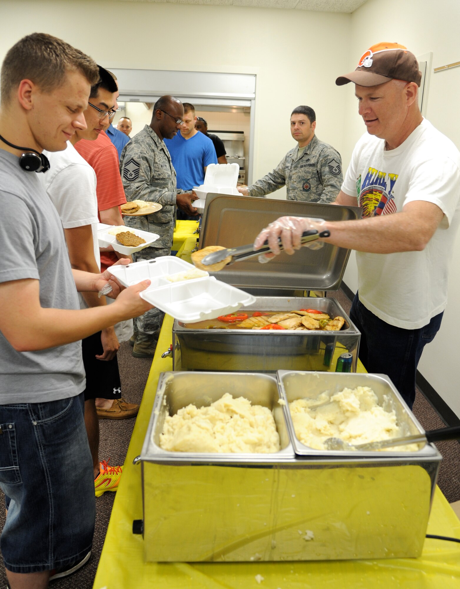 Chief Master Sgt. Mark Aman, right, the 71st Flying Training Wing command chief, serves a chicken breast to Airman 1st Class Bill Logel, a medical administrator with the 71st Medical Support Squadron, during the Singles’ International Gourmet Meal Opportunity, April 30, at Vance Air Force Base, Okla. (U.S. Air Force photo/ Airman 1st Class Frank Casciotta)