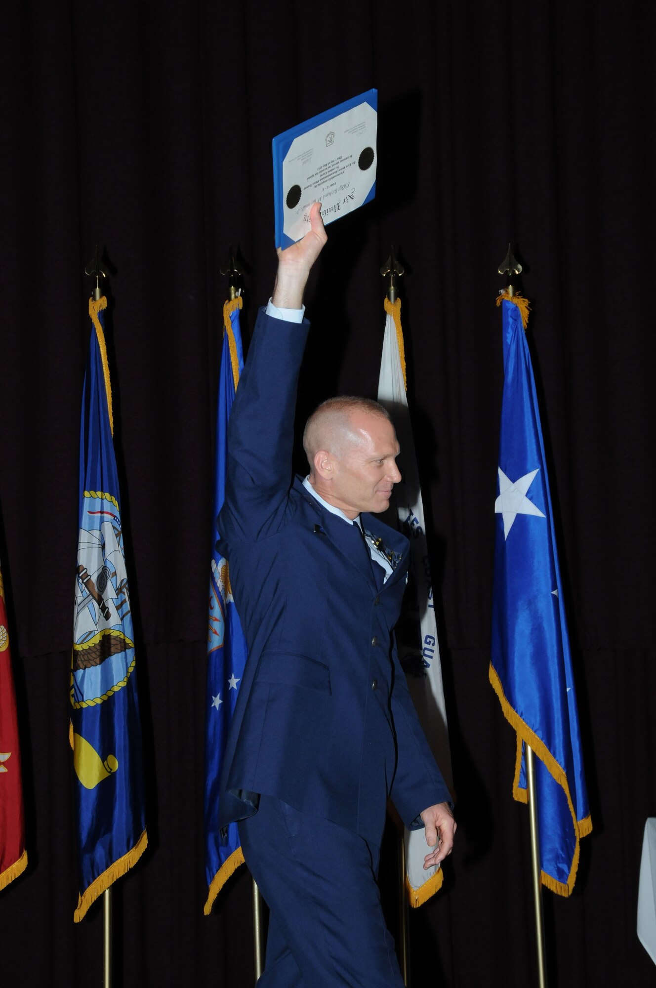 Senior Master Sgt. Richard Reynolds Jr., the class president, holds his degree aloft in celebration at the Air Force Senior NCO Academy graduation Tuesday.