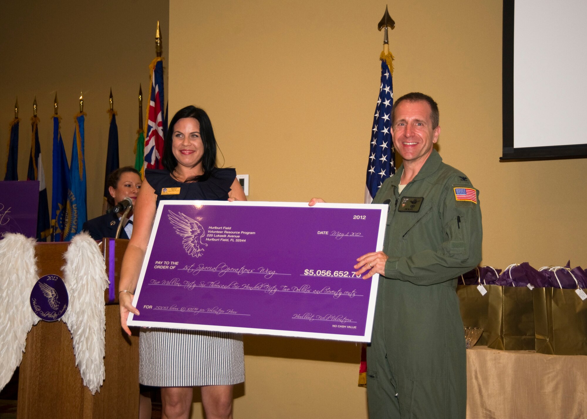 Marisa Ortiz, volunteer coordinator at Airman & Family Readiness Center, presents U.S. Air Force Col. Jim Slife, commander of 1st Special Operations Wing, with a check during the Volunteer Recognition Ceremony at the Soundside Club at Hurlburt Field, Fla., May 1, 2012.  This year, Hurlburt Field?s volunteers efforts helped save the Hurlburt community $5,056,653 in combined hours. (U.S. Air Force photo by Airman 1st Class Naomi M. Griego/RELEASED)
