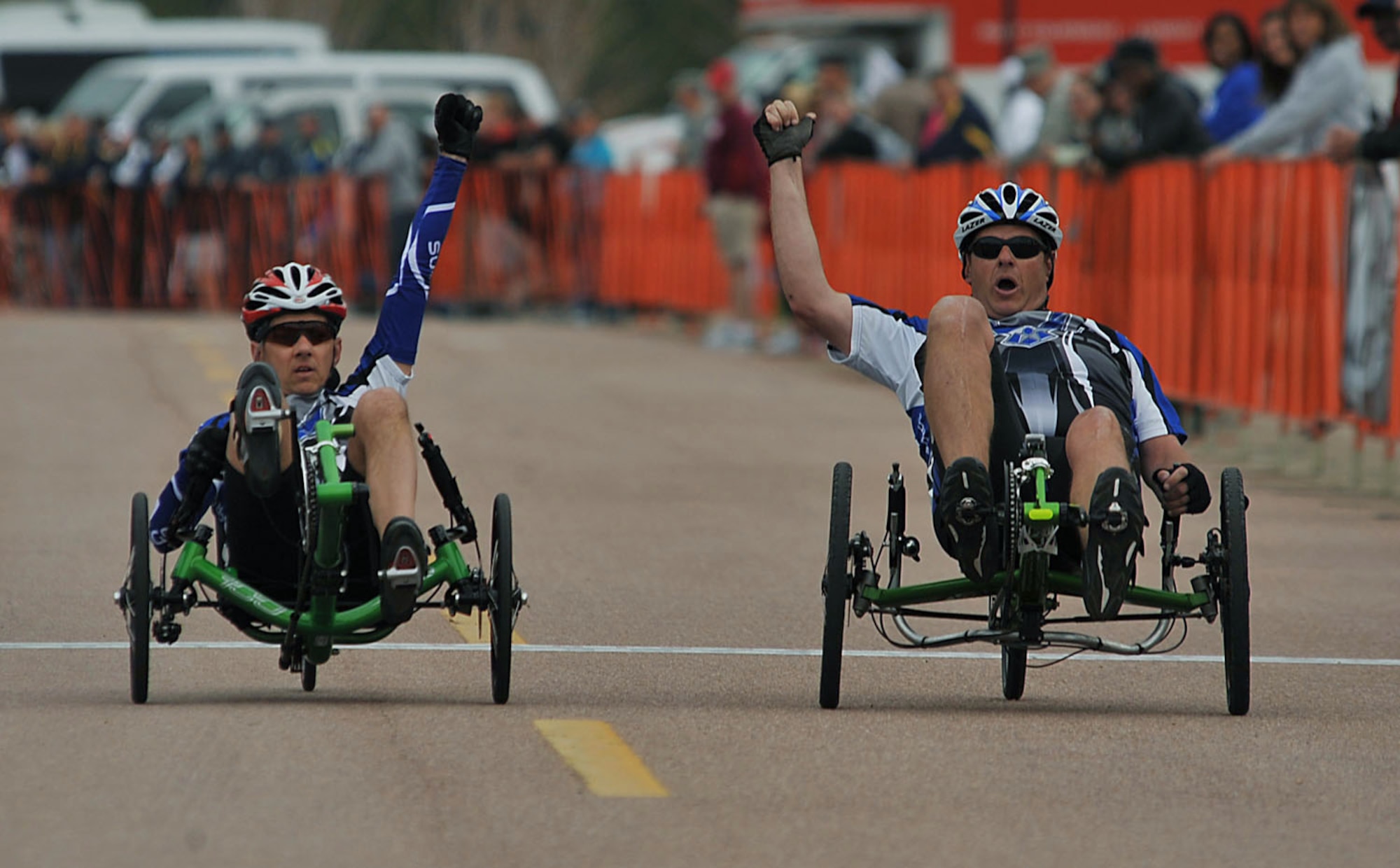 Senior Master Sgt. Mike Sanders (left) and Maj. Scott Bullis raise their hands as they cross the finish line during the recumbent cycling event of Warrior Games 2012 at the U.S. Air Force Academy in Colorado Springs, Colo., May 1, 2012. (U.S. Air Force photo/Val Gempis)