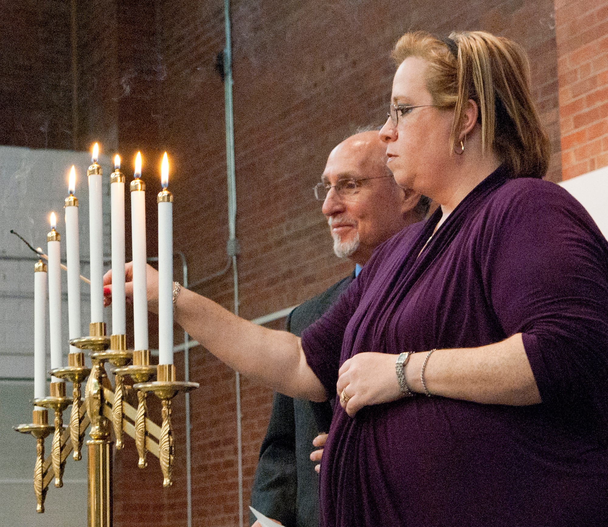 Bonnie Scotto, 90th Missile Wing Judge Advocate Victim Witness Assistance Program coordinator, lights a candle in remembrance of Holocaust victims while Rabbi Harley Karz-Wagman, Mount Sinai Synagogue leader, looks on during the F. E. Warren Air Force Base Holocaust Remembrance and Candle Lighting Ceremony held in the Fall Hall Community Center April 17. Scotto and several other members of the synagogue’s congregation lit the candles in unity with other attendees of the ceremony, who lit candles of their own. (U.S. Air Force photo by Airman Jason Wiese)