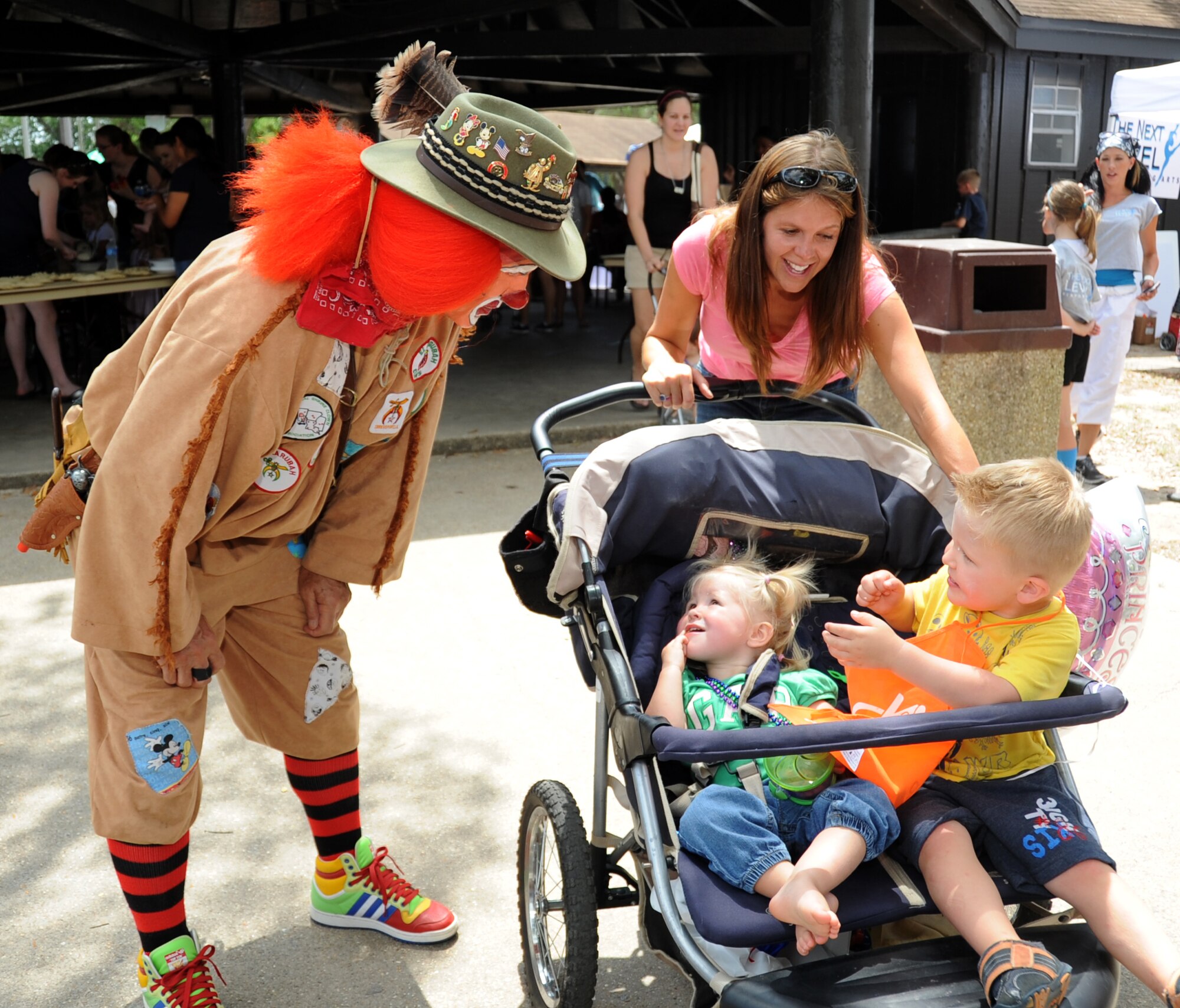 Scout, a clown from the Shriners Temple in Woolmarket, Miss., brings a smile to the faces of Kylynn, 1; Kaeden, 3, and their mom Misty Perry during Child Pride Day April 28, 2012, at Marina park, Keesler Air Force Base, Miss.  Misty’s husband is Capt. Kyle Perry, 81st Inpatient Operation Squadron.  Child Pride Day is an annual event held in conjunction with the month of the military child.  Booths, jumpers, activities, entertainment and food were set up throughout the park.  (U.S. Air Force photo by Kemberly Groue)