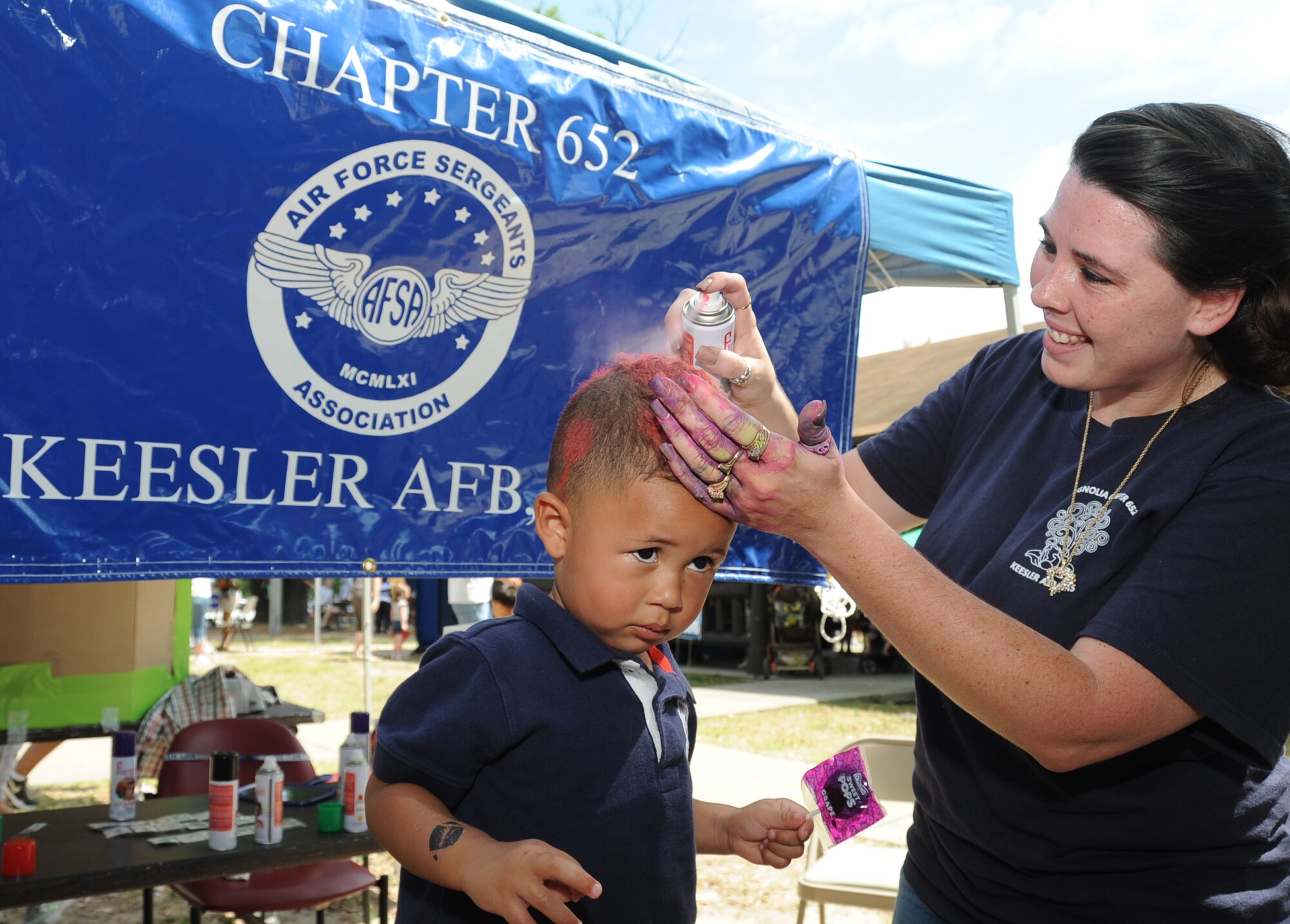 Two-year-old Michael Stafford III, son of Staff Sgt. Michael Stafford II, 334th Training Squadron, has his hair spray painted by Airman First Class Ciara Bien, 81st Medical Support Squadron, at the Air Force Sergeants Association booth during Child Pride Day April 28, 2012, at Marina Park, Keesler Air Force Base, Miss.  Child Pride Day is an annual event held in conjunction with the month of the military child.  Booths, jumpers, activities, entertainment and food were set up throughout the park.  (U.S. Air Force photo by Kemberly Groue)