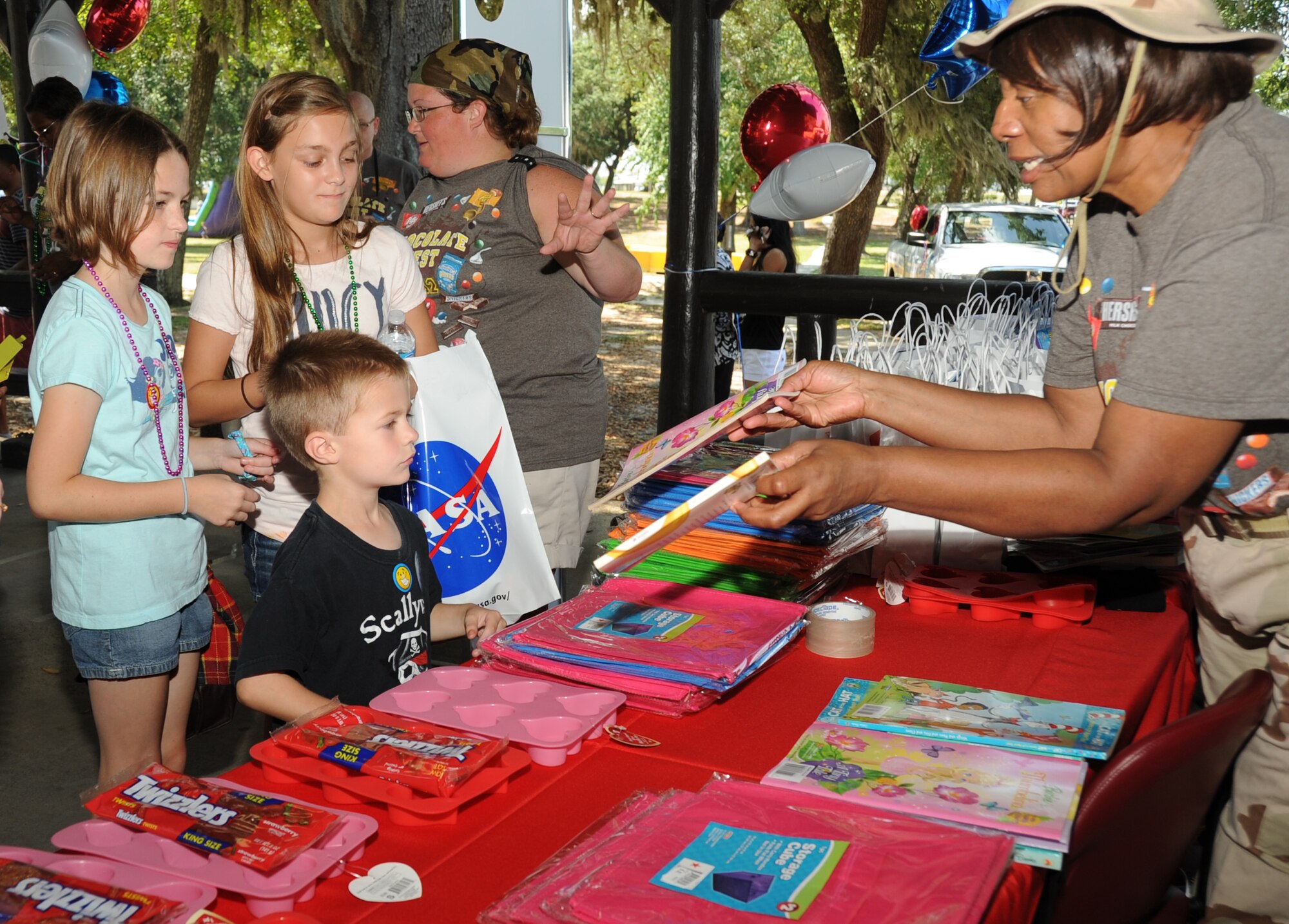 Hannah, 10, her brother, Carson Holbert, 10, and their friend, Anniston Warrick, 10, receive giveaways from Ruth Tolbert, AFEES senior office assistant at the Keesler Exchange, during Child Pride Day April 28, 2012, at Marina Park, Keesler Air Force Base, Miss.  Hannah and Carson’s dad is Master Sgt. Jason Holbert, 81st Training Support Squadron.  Anniston’s parents are Jackie and Jeff Warrick of St. Martin.   Child Pride Day is an annual event held in conjunction with the month of the military child.  Booths, jumpers, activities, entertainment and food were set up throughout the park.  (U.S. Air Force photo by Kemberly Groue)