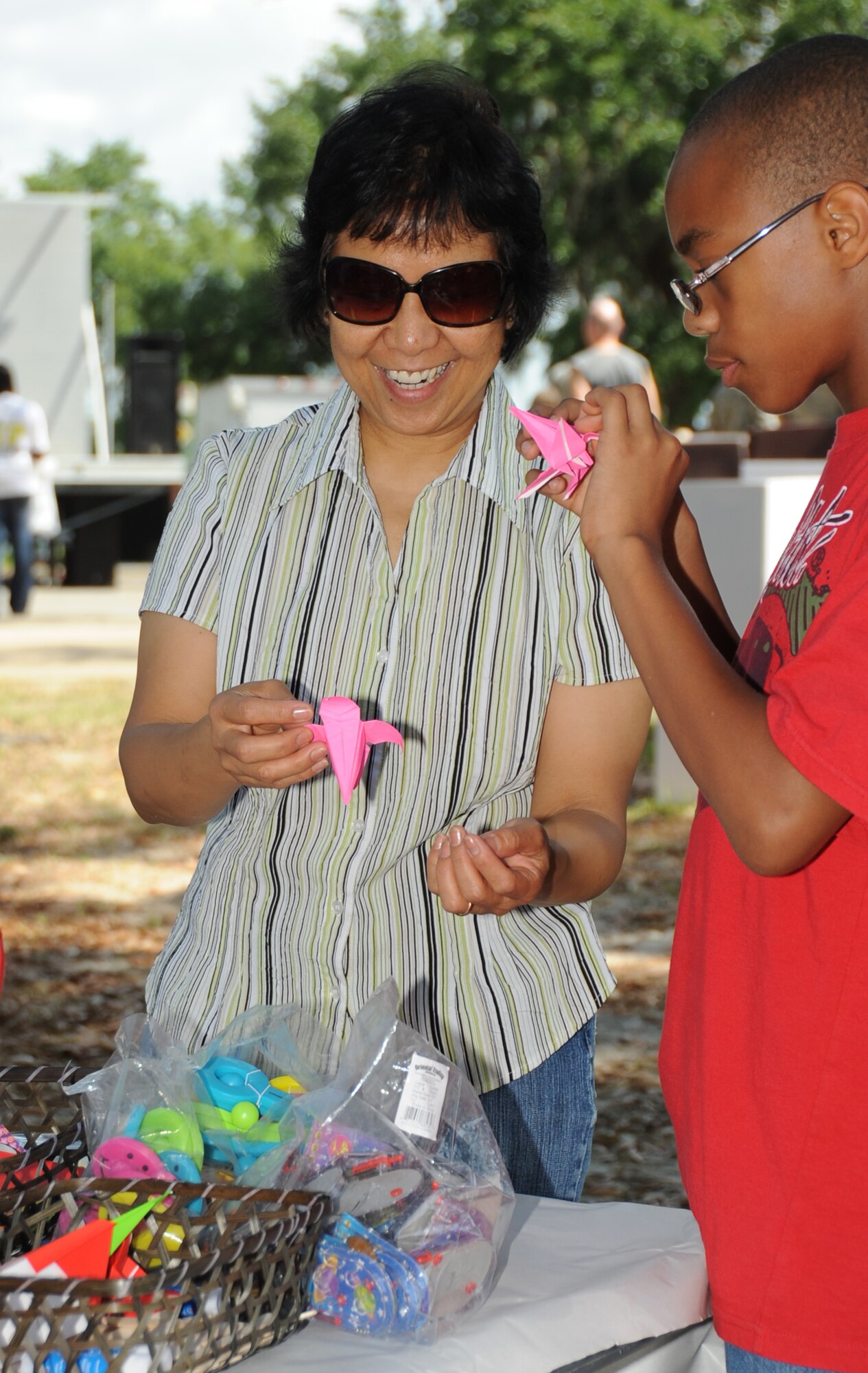 Retired Master Sgt. Evangeline Villanueva and Gregory Jones III, 11, son of Rachel and Tech Sgt. Gregory Jones Jr., 81st Medical Operations Squadron, make origami at the Asian Pacific Heritage  booth during Child Pride Day April 28, 2012, at Marina Park, Keesler Air Force Base, Miss.  Child Pride Day is an annual event held in conjunction with the month of the military child.  Booths, jumpers, activities, entertainment and food were set up throughout the park.  (U.S. Air Force photo by Kemberly Groue)