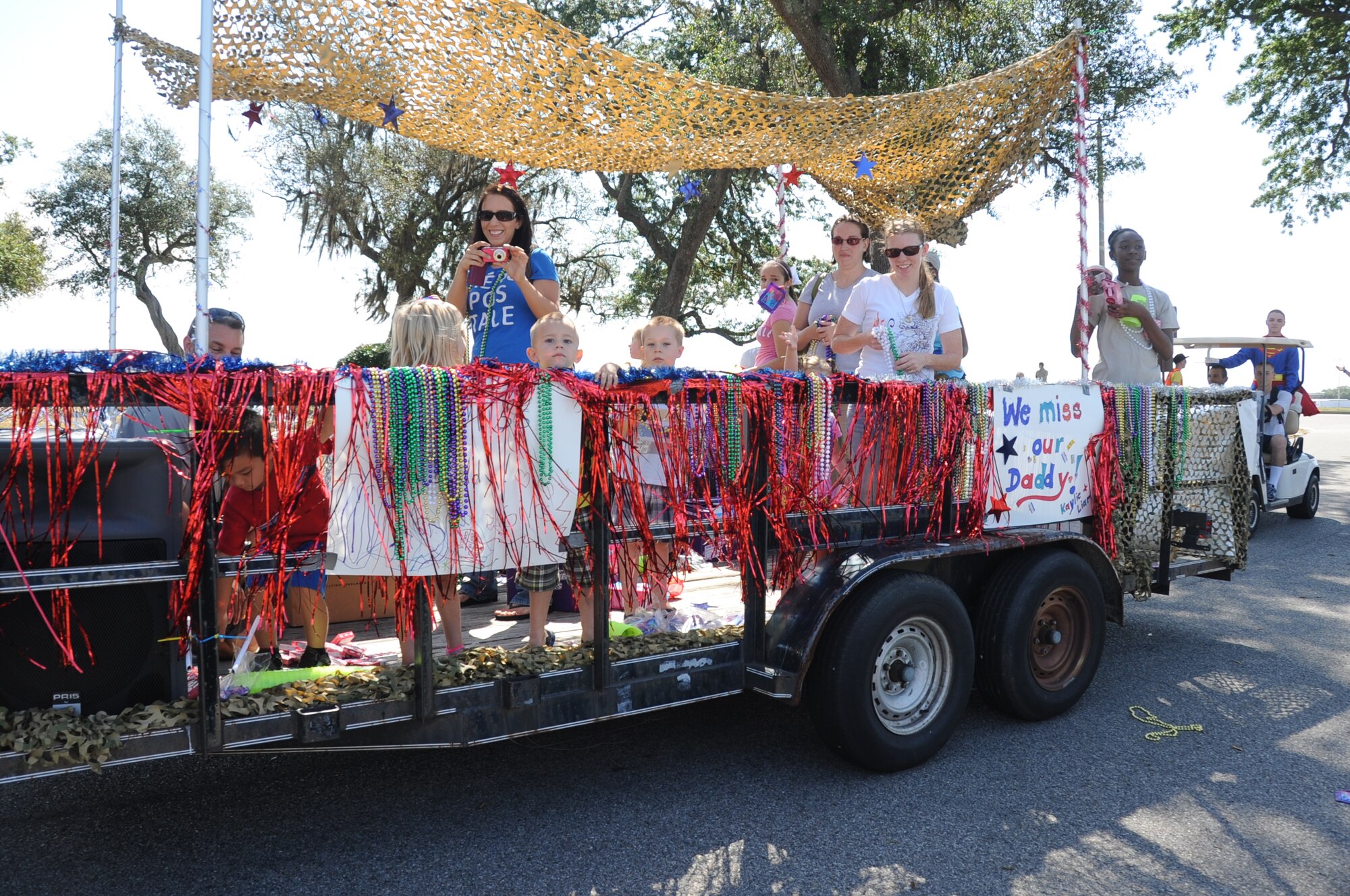 A parade kicked off Child Pride Day April 28, 2012, at Keesler Air Force Base, Miss. In this float, families of deployed members toss candy and beads to the crowd lining the parade route at the marina park.  Child Pride Day is an annual event in collaboration with the month of the military child.  Booths, jumpers, activities, entertainment and food were set up throughout the park.  (U.S. Air Force photo by Kemberly Groue)