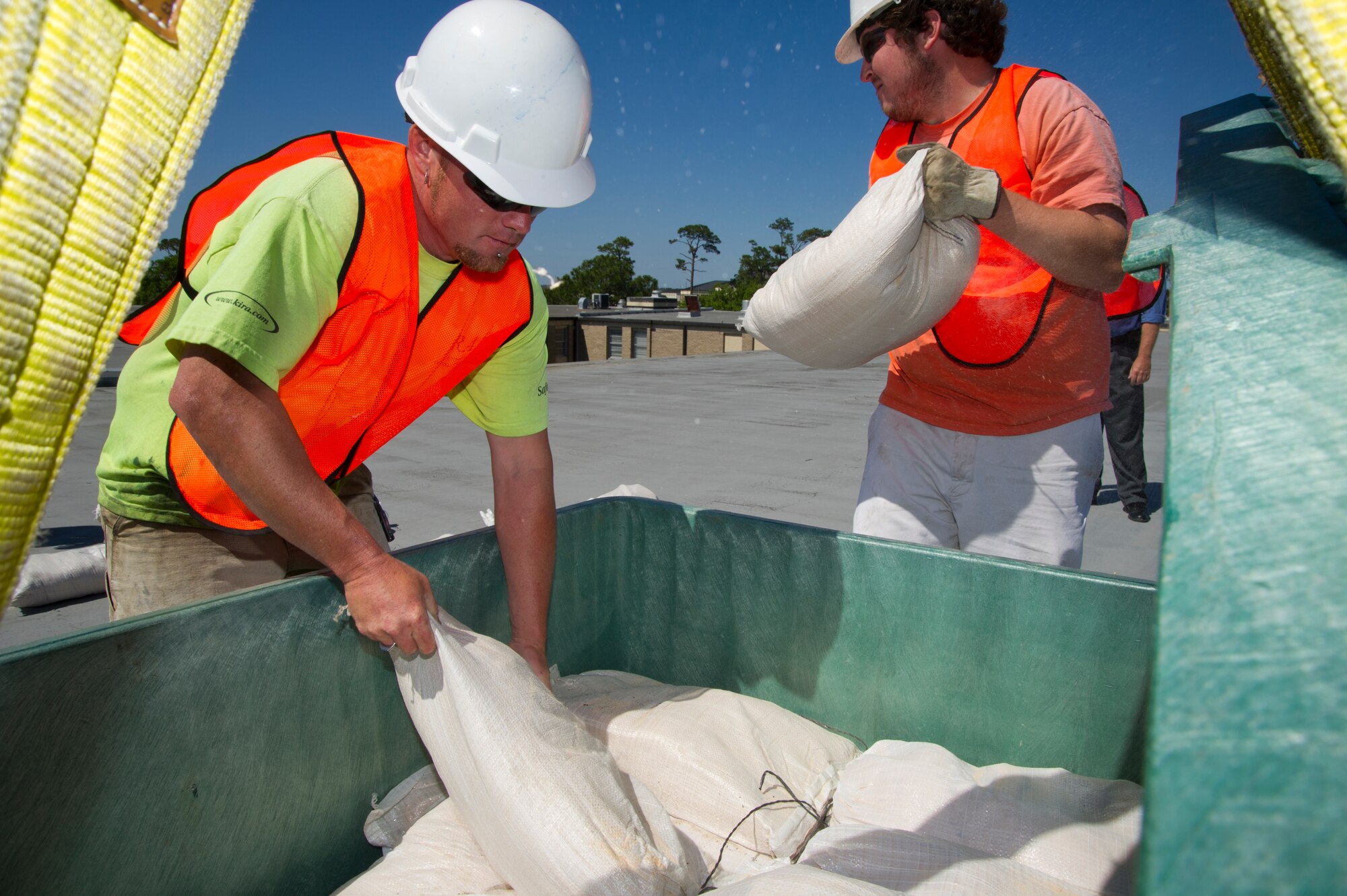 Nick Ellzey (left) and Tim Goad, CSC, deploy sandbags onto the Locker House roof during a hurricane condition exercise April 25, 2012, at Keesler Air Force Base, Miss. The sandbags are intended to reduce wind damage to the building’s roof.  The exercise was held in preparation for the 2012 hurricane season which runs from June 1 to Nov. 30.  (U.S. Air Force photo by Adam Bond)