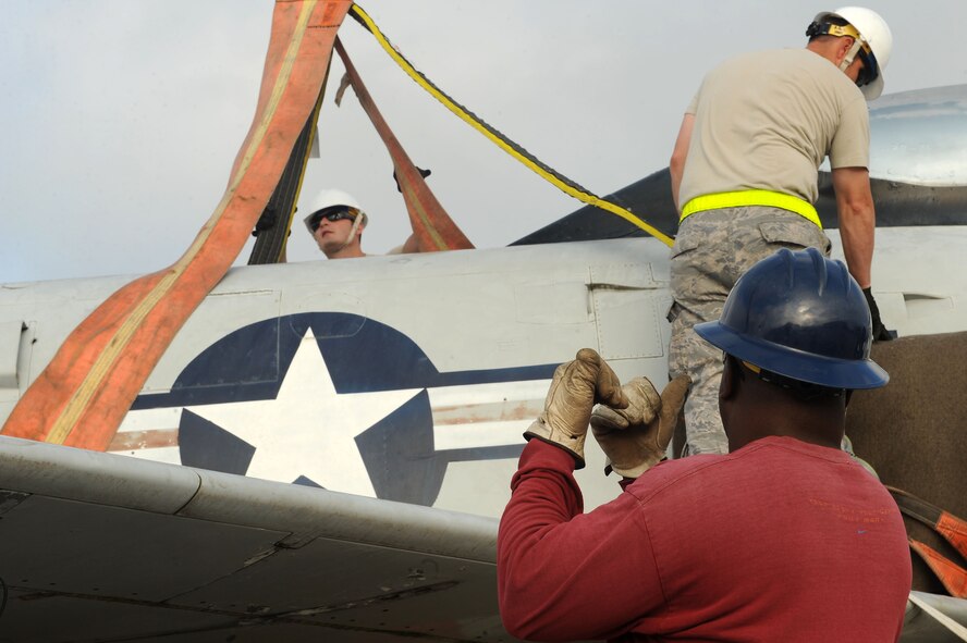 Reginald Patrick, 23d Civil Engineer Squadron heavy equipment operator, directs crane movement as Airmen secure straps on an F-86L Sabre at Moody Air Force Base, Ga., May 1, 2012. The crane transferred an F-86L Sabre from a flatbed truck to a pallet for renovations. (U.S. Air Force photo by Staff Sgt. Ciara Wymbs/Released)  