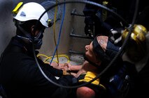 Dwayne Peeples, Schriever Fire Department firefighter, secures a “victim” for lift during confined-space training May 1 at Schriever Air Force Base. During the training, the firefighters learned how to integrate equipment and personnel as well as plan for tactics and strategies to remove a victim from confined spaces. (U.S. Air Force photo/Staff Sgt. Julius Delos Reyes)