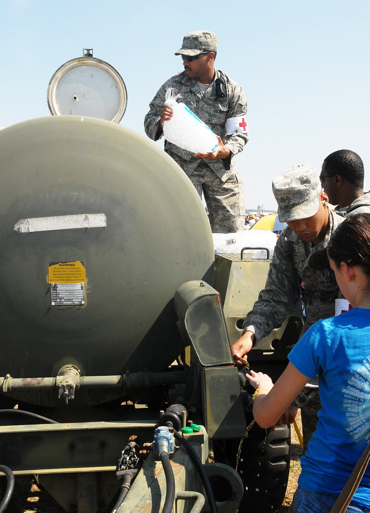 Airman 1st Class Darryl Adams, top center, 78th Medical Group, adds ice to a drinking water supply tank at Robins Air Show 2012 (U. S. Air Force photo by Sue Sapp)