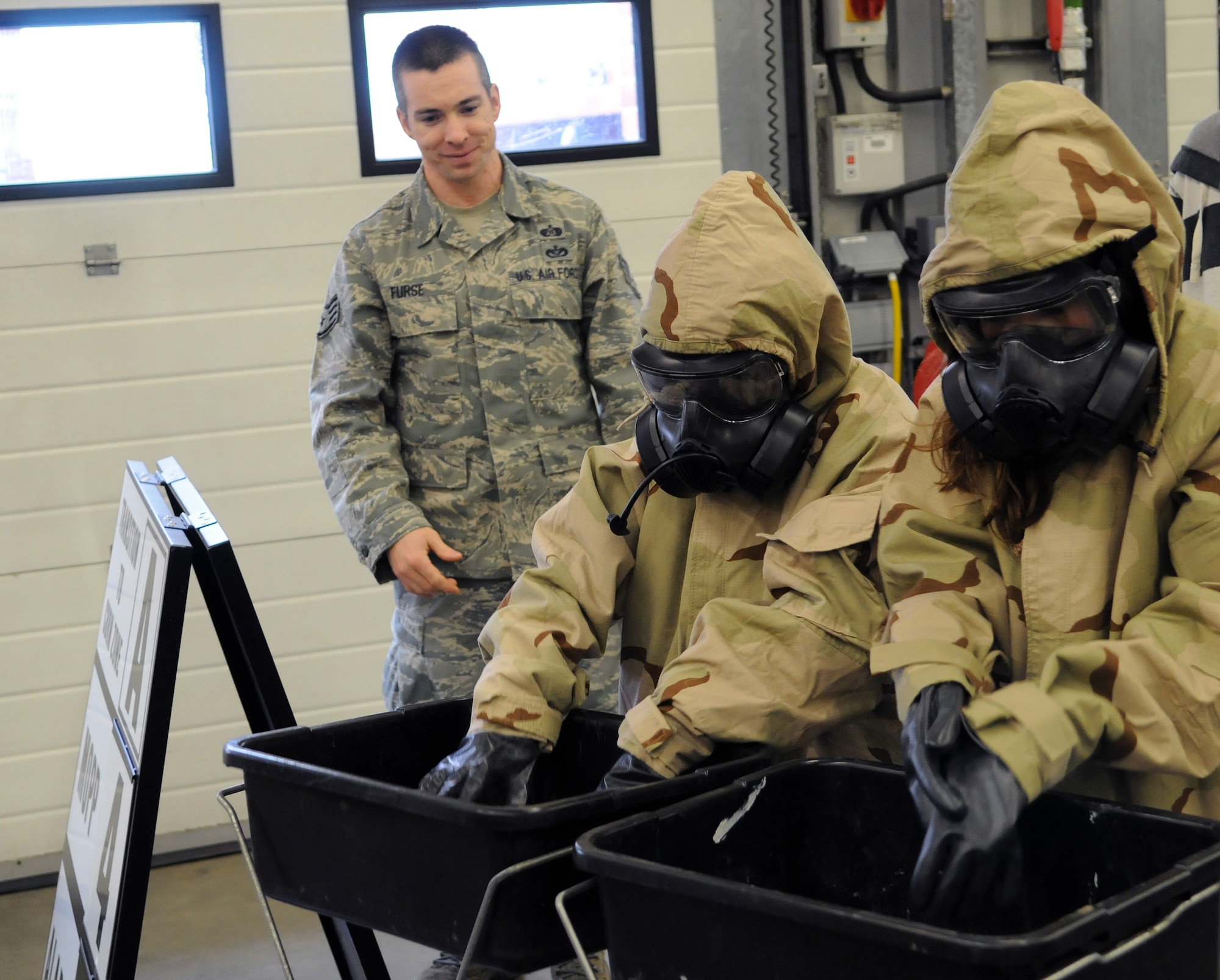 “The gas masks are just like in zombie movies. They make it hard to see and breathe,” said 8-year-old Scott Trower, a photojournalist for the day. (Two participants of Job Shadow Day here April 27, 2012, “decontaminate” themselves under the guidance of Staff Sgt. Jesse Furse, 100th Civil Engineer Squadron. Learning to be a photojournalist, like his father who works at the 100th Air Refueling Wing Public Affairs office, 3rd-grader Scott documented the day’s events.) (U.S. Air Force photo/Scott Trower)