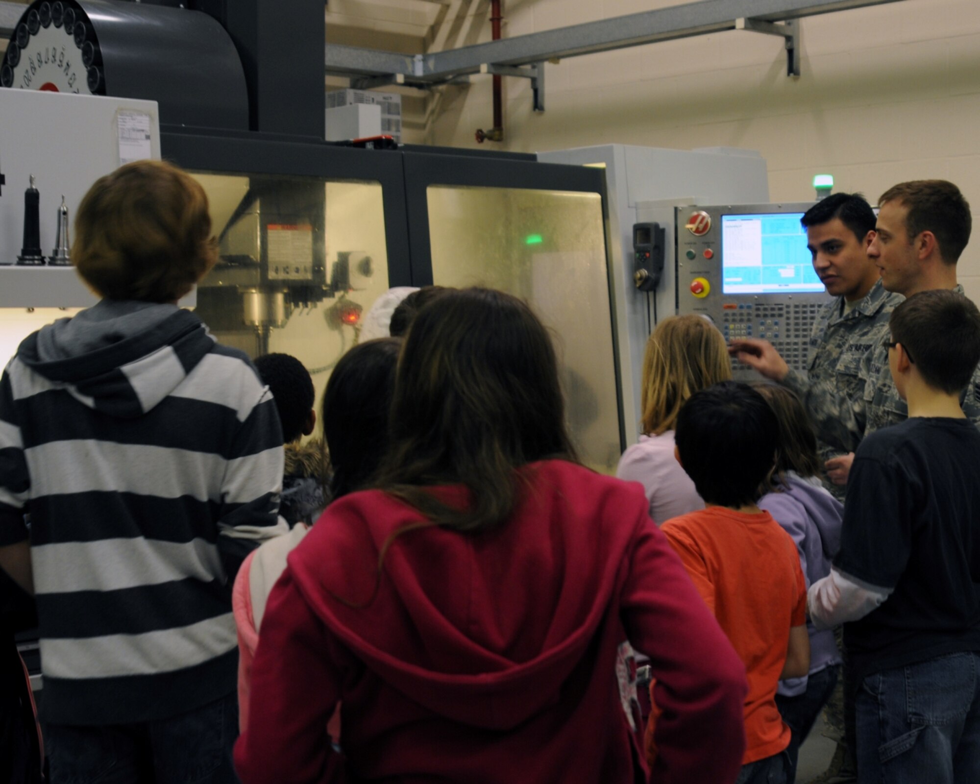 “When I first saw the cutting machine, I thought it looked like a shower working with hot water but the machine could actually cut through metal,” said 2nd grader Hannah Smith, a photojournalist for the day. (Metals Technology mechanics from the 100th Maintenance Squadron demonstrate a high-tech metal cutting machine for a group of base children during Job Shadow Day here April 27, 2012. Learning to be a photojournalist, like her father who works at the 100th Air Refueling Wing Public Affairs office, 7-year-old Hannah Smith captures the demonstration on her camera.) (U.S. Air Force photo/Hannah Smith)