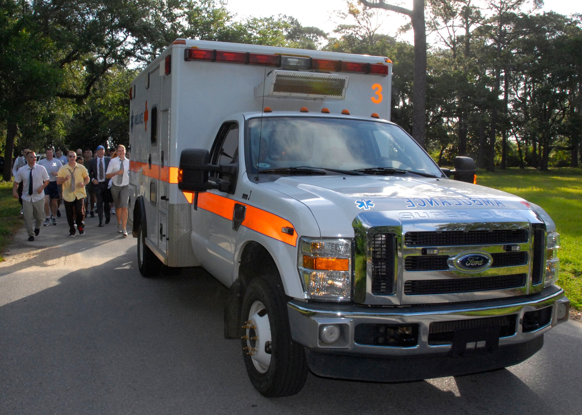 Military and civilian personnel, some dressed as lawyers, chase after an ambulance during the 5k Ambulance Chase at Eglin Air Force Base, Fla., May 2.  The run was part of the Staff Judge Advocate office’s Law Day activities.  (U.S. Air Force photo/Kevin Gaddie)