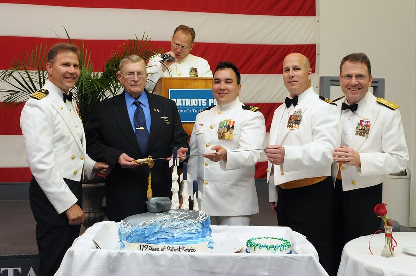 (Left to right) Capt. John Fahs prepares to cut a ceremonial cake with John Hill, Lt. Karl Sault, Cmdr. Mark Schmitt and Adm. Joseph Tofalo at the Submarine Ball onboard USS Yorktown at Patriots Point Maritime Museum April 27. The ball was in celebration of 112 years of U.S. Navy submarine service. Fahs is the Navy Nuclear Power Training Command commanding officer, Hill is a World War II submarine veteran, Sault is the most junior qualified submariner in attendance, Schmitt is the most senior qualified submariner in attendance and Tofalo is the Submarine Group 10 commander. (U.S. Navy photo/Petty Officer 1st Class Jennifer Hudson)