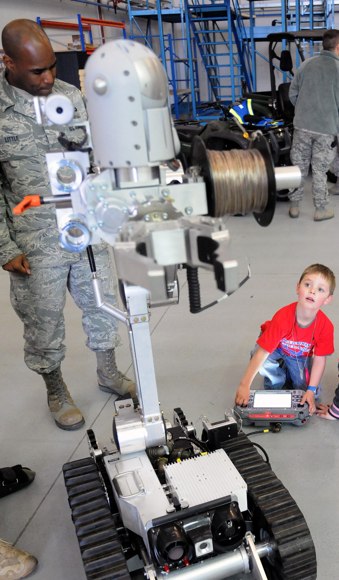 RAF MILDENHALL, England -- Staff Sgt. Gevoyd Little, 48th Civil Engineer Squadron Explosive Ordinance Disposal flight, lets AJ, son of Capt. Kevin Haynie, 351st Air Refueling Squadron, control the camera on robotic equipment the flight uses to assess and disable explosives on deployments during Operation Together and Ready here April 28, 2012. Phase II of the deployment scenario allowed the children of Airmen to experience a part of the deployment process. (U.S. Air Force photo/Staff Sgt. Thomas Trower)
