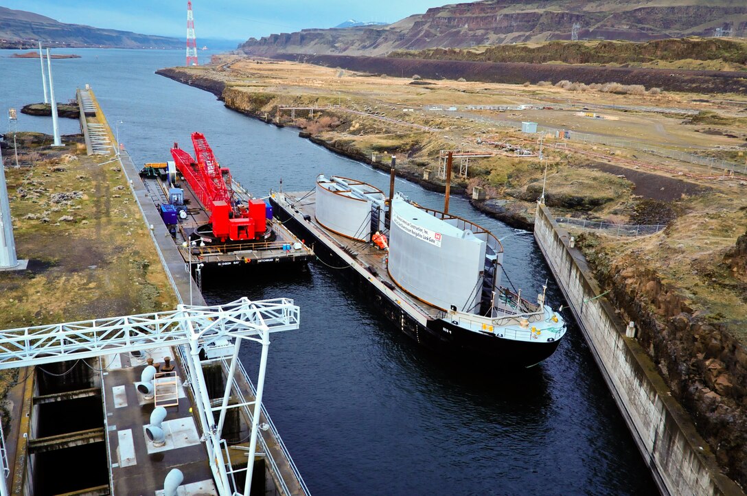 A barge with two new navigation lock friction sheaves and a Manitowoc Model 888 crane passes through Bonneville Lock and Dam on Dec. 1, 2010, heading for John Day Lock and Dam.
Photos of the JD gate sections and crane moored just below the navlock, and a tug moving the floating bulkhead into position to seal the downriver entry prior to dewatering, which began Dec. 10, 2010.
