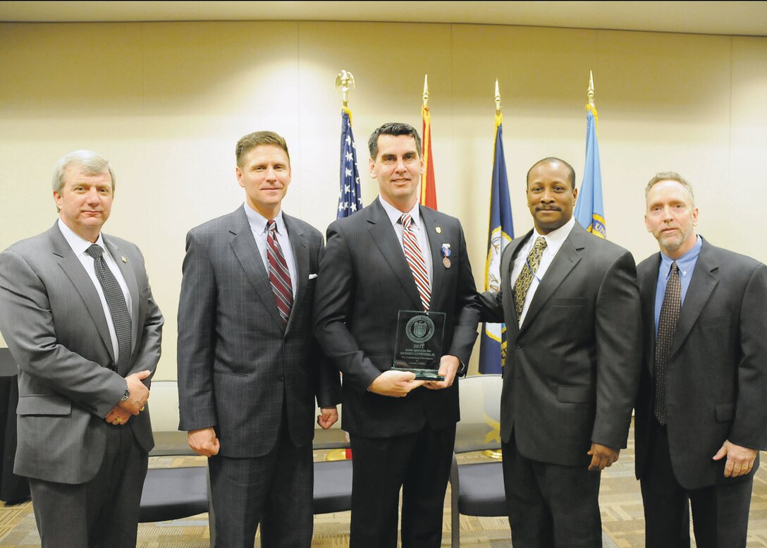 Rick Dunwoodie, center, Naval Criminal Investigative Service special agent, Marine Corps Logistics Base Albany, receives the 2011 NCIS Special Agent of the Year for Criminal Investigations award during a recent ceremony at the NCIS headquarters in the Russell Knox building, Quantico, Va.
