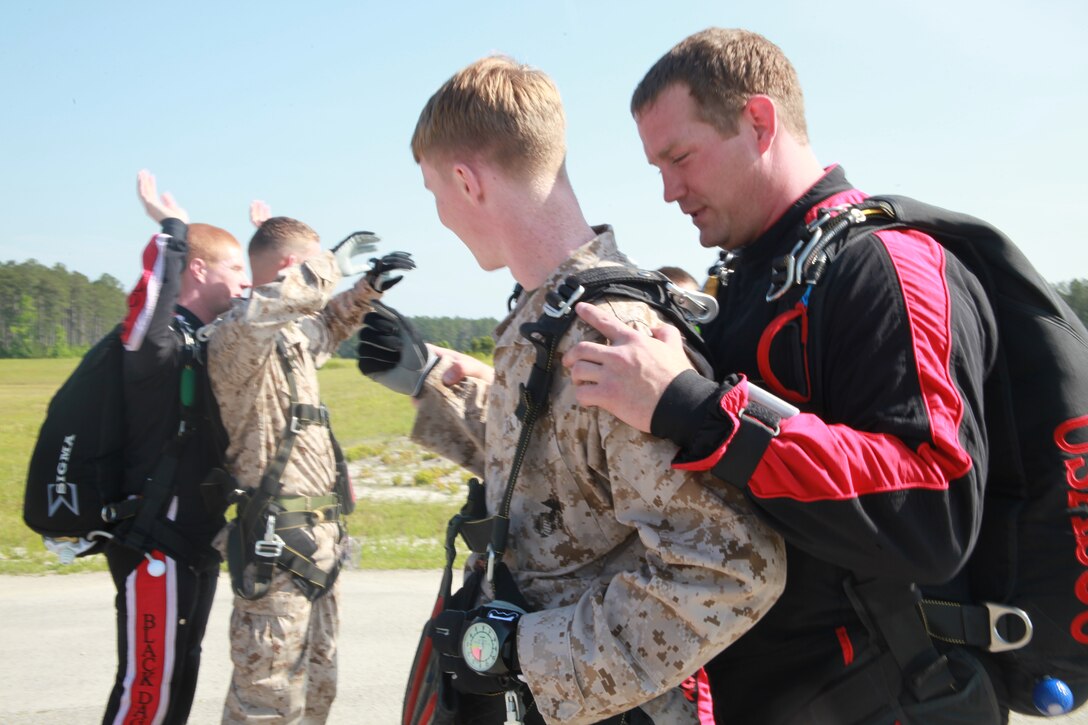 Two Marines, Cpl. Kyle Smith, a rescue diver with Marine Transport Squadron 1, and Cpl. Kevin Willis, an aircraft electronic countermeasures technician with Marine Tactical Electronic Warfare Squadron 4, go through one last gear check before completing their tandem skydive the United States Army Special Operations Command Black Daggers May 3.  The Marines jumped with one of the Black Daggers strapped to their backs and were allowed to pull the cord as they freefell to the earth.