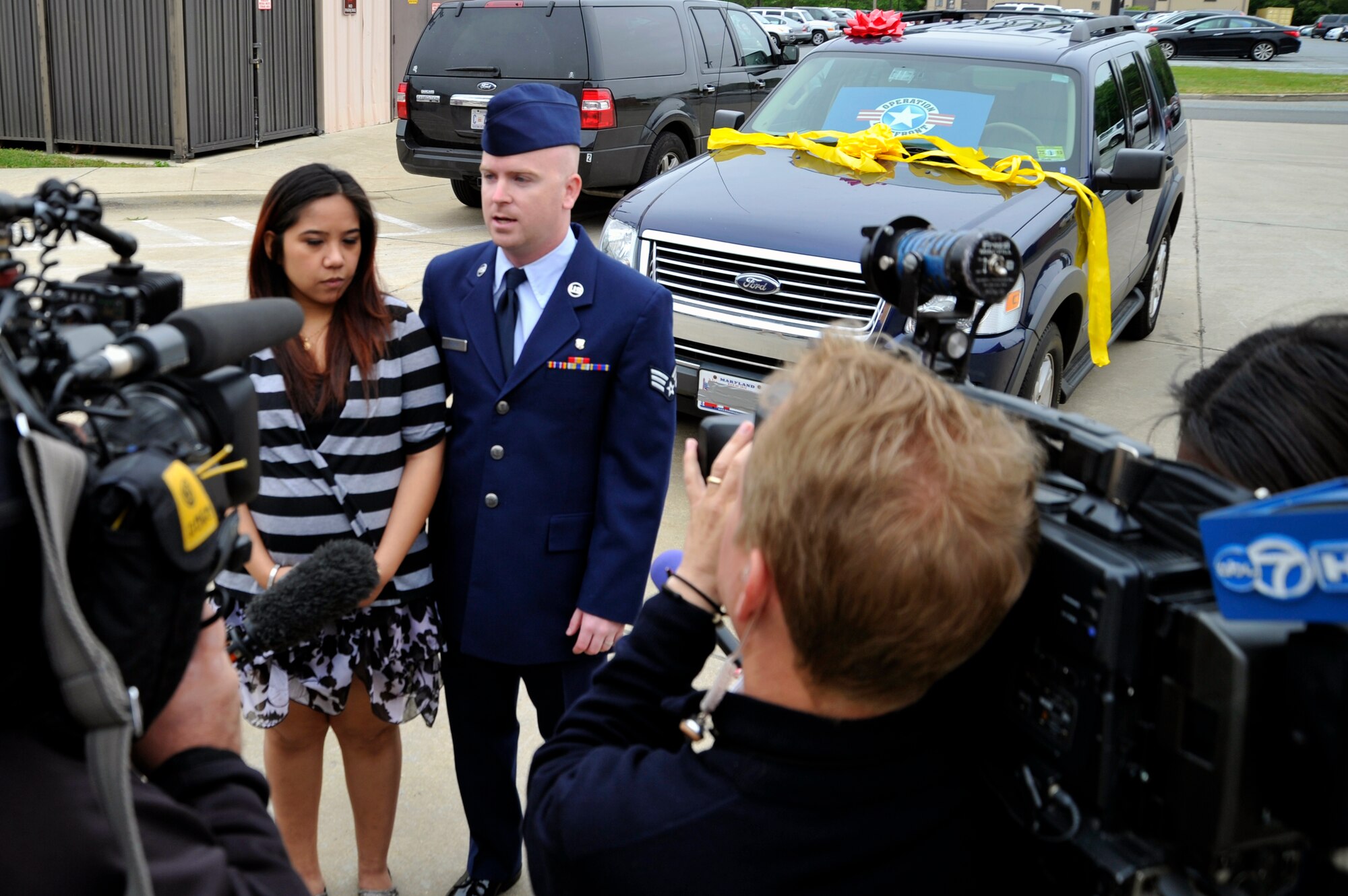 Senior Airman Aaron Becker, 779th Medical Group biomedical equipment technician, and his wife, Mercy, speak to local media April 30 after receiving a 2009 Ford Explorer courtesy of Operation Homefront. (U.S. Air Force Photo/Senior Airman Perry Aston)