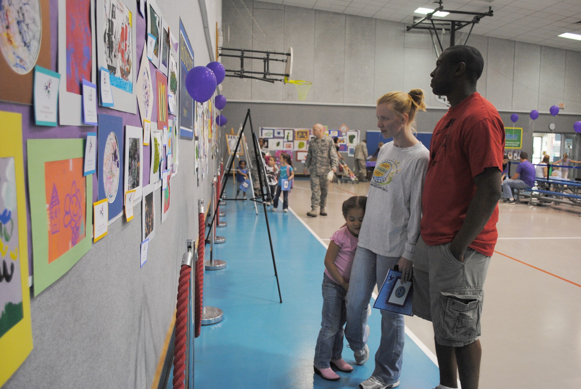 Airman 1st Class Rashard Winn, 819th RED HORSE Squadron structural apprentice, right, his wife Ashley, and their daughter Ryleigh, 4, browse the artwork at the Youth Center April 26. More than 240 children participated in the art show, which featured all recycled items. The center accepted artwork from children as old as 18 and includes art from home-schooled students as well. Complete with music, cookies and cupcakes, the center hopes to make the art show an annual event. (U.S. Air Force photo/Airman 1st Class Katrina Heikkinen)