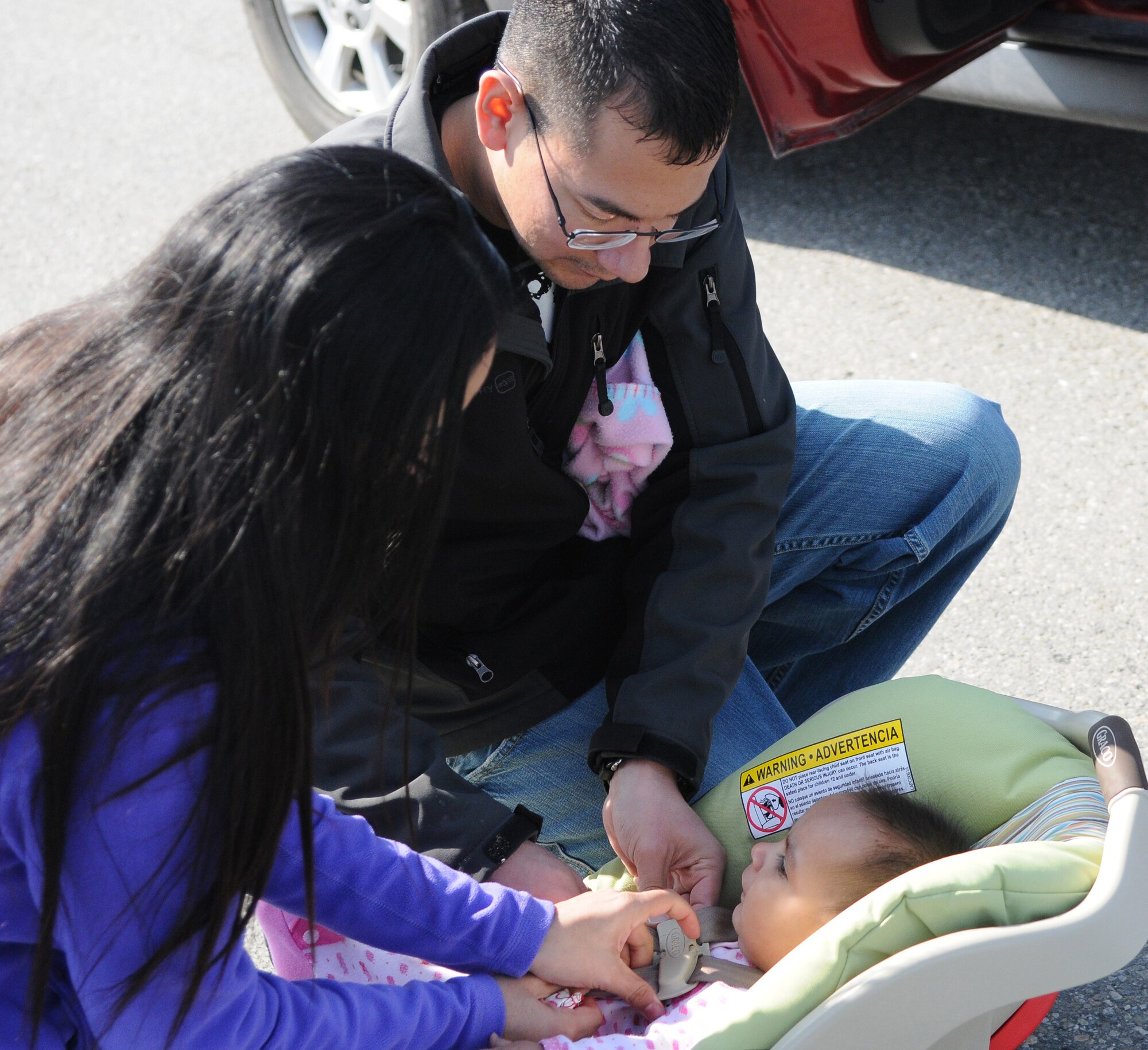 U.S. Army Spc. Pablo Carrillo, a Ft. Wainwright 5/1 Cavalry infantryman, and his wife, Heidi, secure their seven-month-old, Sophia, into her car seat after base firefighters inspected the seat April 28, 2012, Eielson Air Force Base, Alaska. By using checklists and ensuring an infant or child is not only comfortable but safe, parents were able to leave the fire station knowing their child had been provided with safety measures tested for that specific seat. (U.S. Air Force photo/ Senior Airman Janine Thibault)