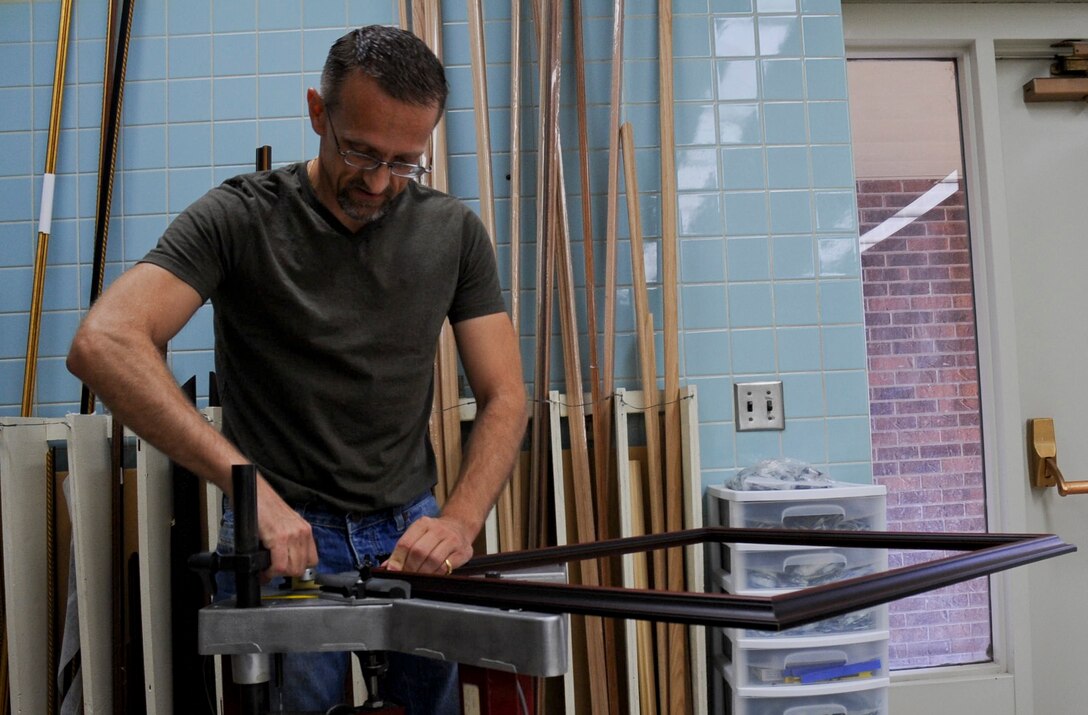 Travis Bolt, 28th Force Support Squadron Arts and Crafts Center volunteer, locks a frame into place on a frame joining machine at the Arts and Crafts Center at Ellsworth Air Force Base, S.D., May 2, 2012. The frame joiner reinforces the corners of the frames during construction. (U.S. Air Force photo by Airman 1st Class Anania Tekurio/Released)