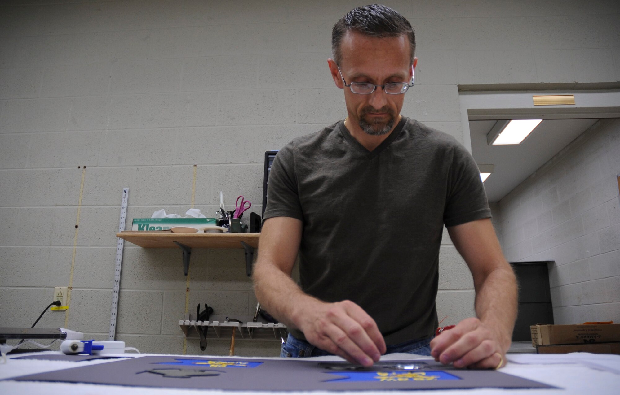 Travis Bolt, 28th Force Support Squadron Arts and Crafts Center volunteer, places a squadron coin into a a going away gift at the Arts and Crafts Center at Ellsworth Air Force Base, S.D., May 2, 2012. A wide array of framing, printing, engraving, carving and similar services are available at the center. (U.S. Air Force photo by Airman 1st Class Anania Tekurio/Released)