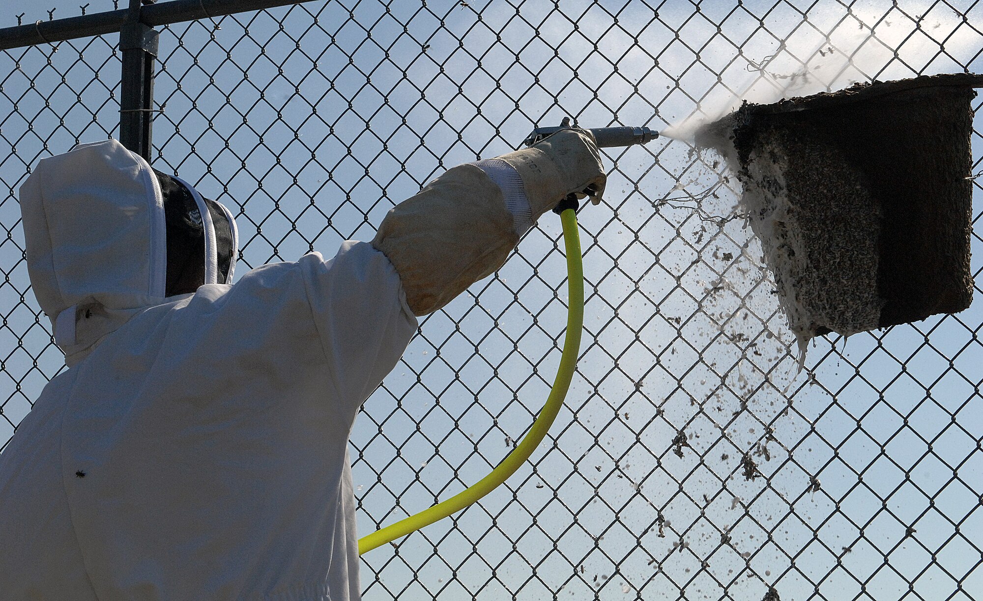Staff Sgt. Terri Williams, 7th Civil Engineer Squadron pest management specialist, sprays a beehive May 1, 2012, at Dyess Air Force Base, Texas. Each hive releases a custom pheromone to attract the bees away from base population and to these designated locations. Pest Management specialists work to keep bases free of all pests, ranging from insects to rodents. (U.S. Air Force photo by Airman 1st Class Charles V. Rivezzo/ Released)