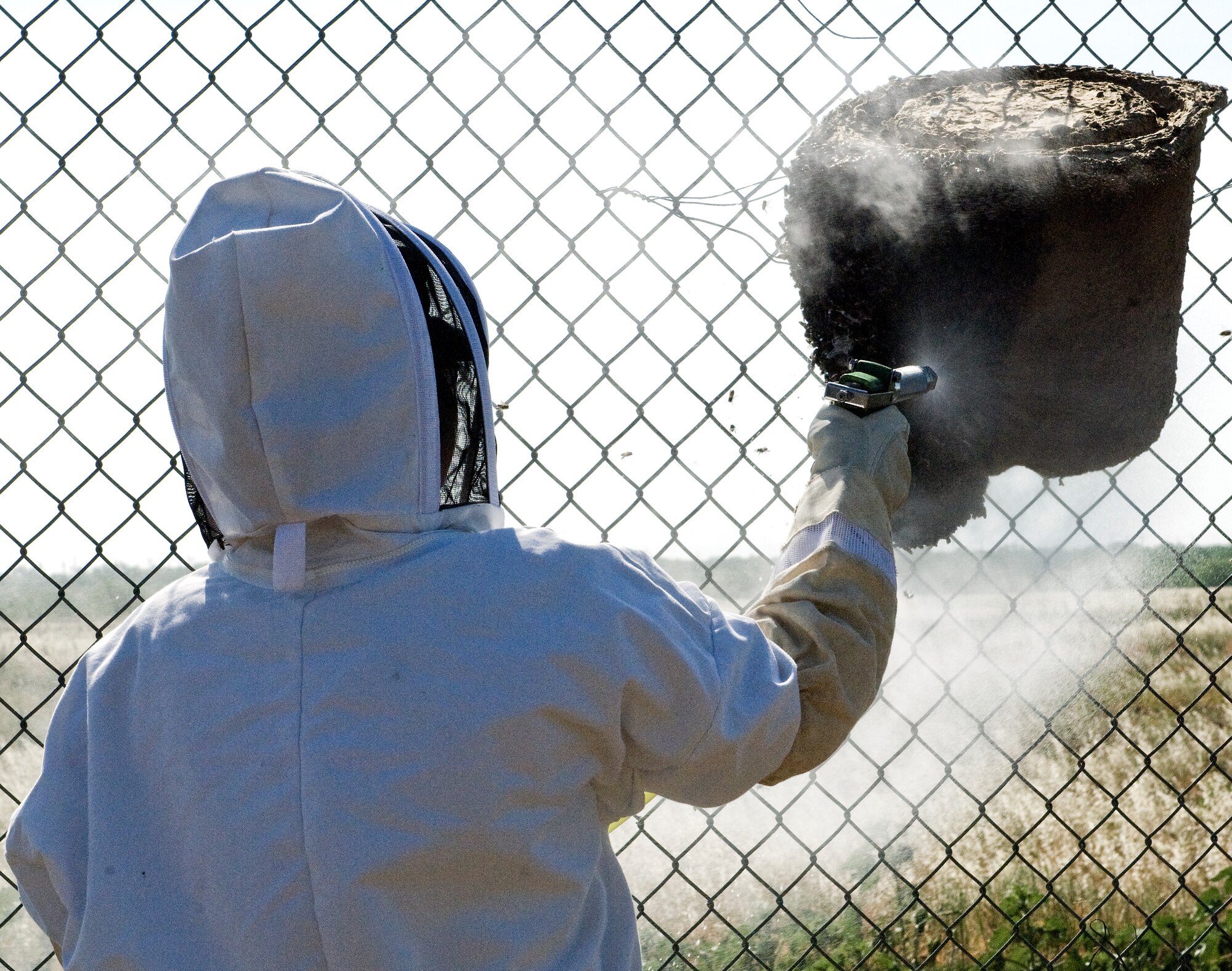 Staff Sgt. Terri Williams, 7th Civil Engineer Squadron pest management specialist, sprays a beehive May 1, 2012, at Dyess Air Force Base, Texas. Each hive releases a custom pheromone to attract the bees away from base population and to these designated locations. Pest Management specialists work to keep bases free of all pests, ranging from insects to rodents. (U.S. Air Force photo by Airman 1st Class Charles V. Rivezzo/ Released)