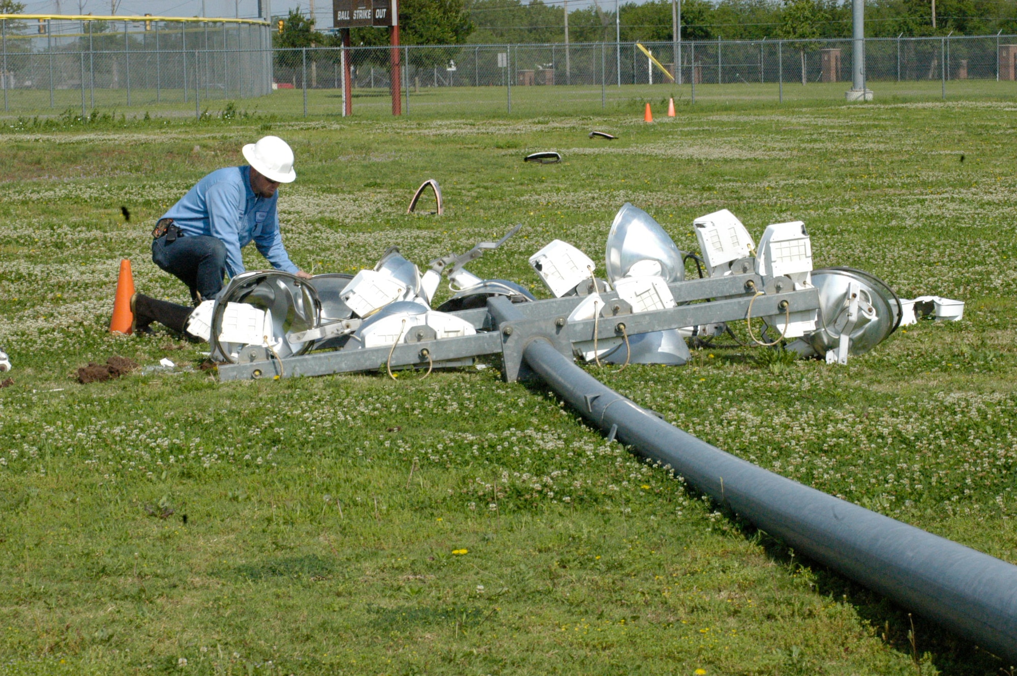 Kevin Rayburn of Tinker Support Services examines a light pole laying in the outfield of Tinker softball field No. 2, along the first-base line, Monday. The 65-foot pole blew over in high wind April 27, apparently because of a stress fracture at its base, Rayburn said. (Air Force photo by Mike Ray)
