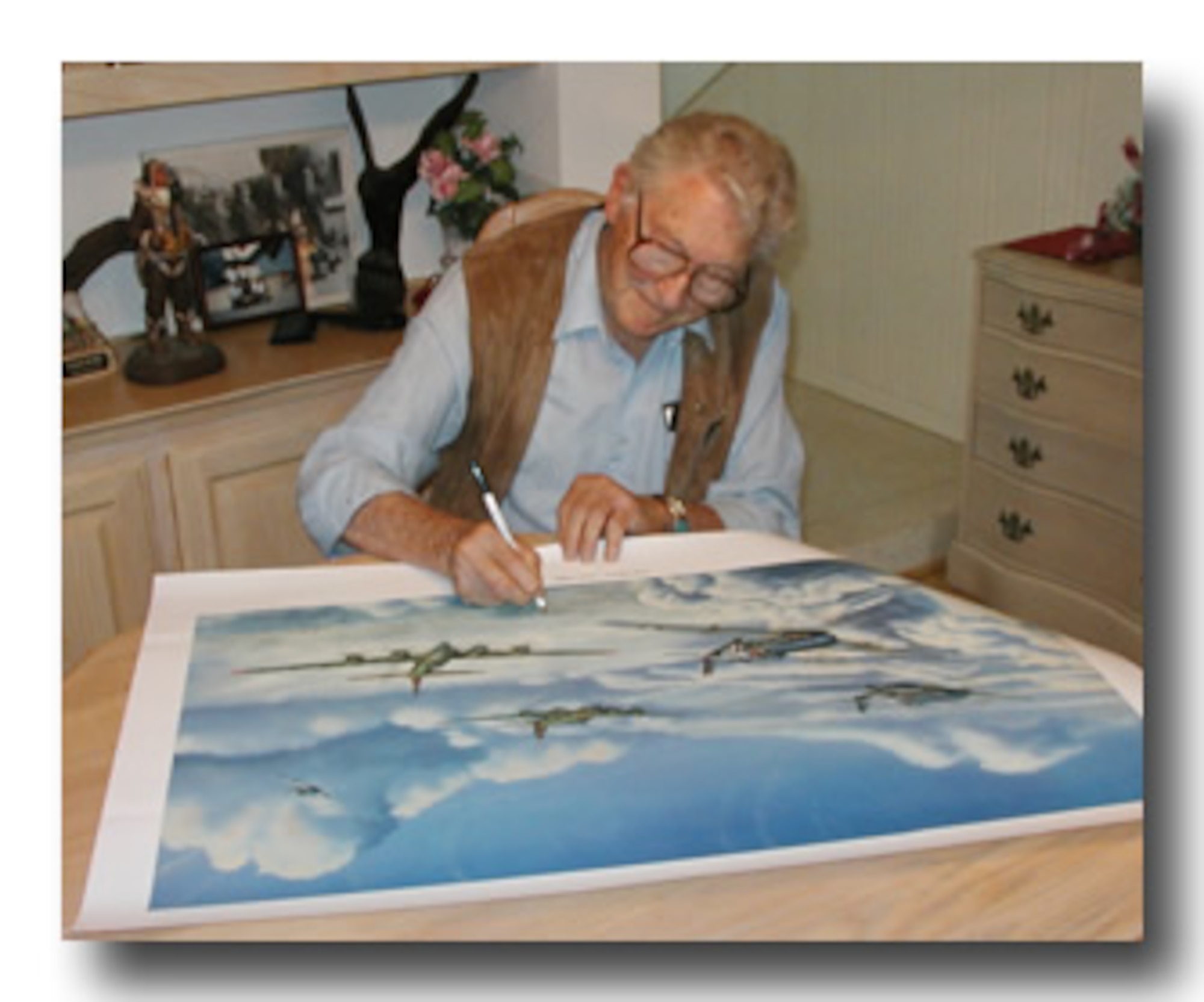 Andy Anderson, a pilot who was assigned to the 91st Bombardment Group, now the 91st Missile Wing, signs a lithograph called Full House - Aces High. On Sept. 5, 1944, Anderson was assigned as an experienced combat pilot on a mission to Ludwigshafen, Germany, which ended in a crash behind enemy lines. (Courtesy photo)

