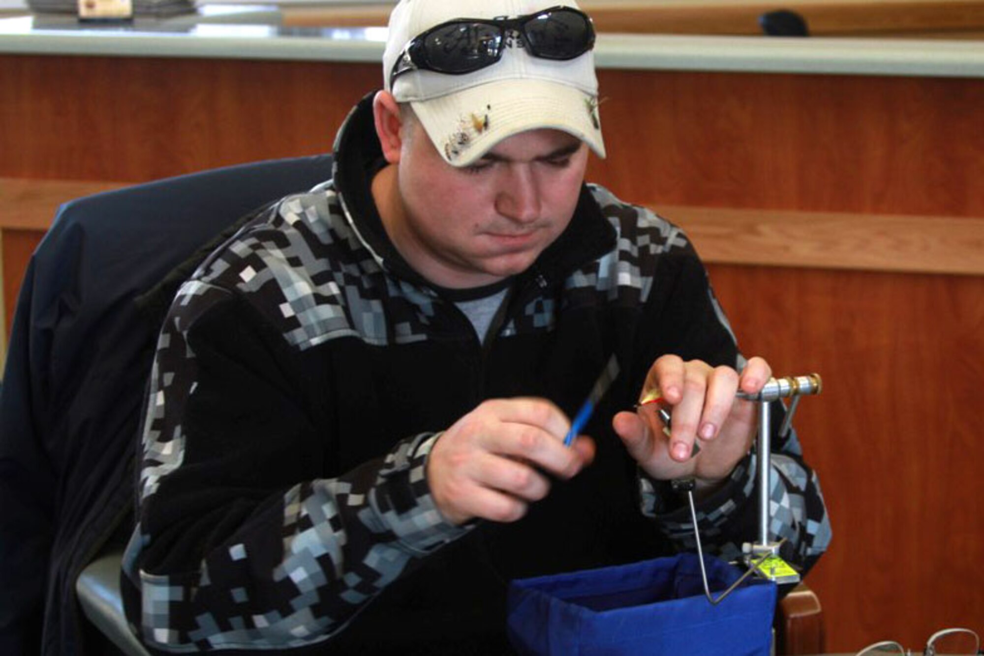 Senior Airman Justin Hendrick volunteers his time April 12 at the Healing Waters fly tying class. Healing Waters is a project sponsored by Alaska Fly Fishers that provides recovering veterans a change of pace from the often daily routine of medical and physical appointments.  (U.S. Army photo/Spc. Juana Nesbitt)