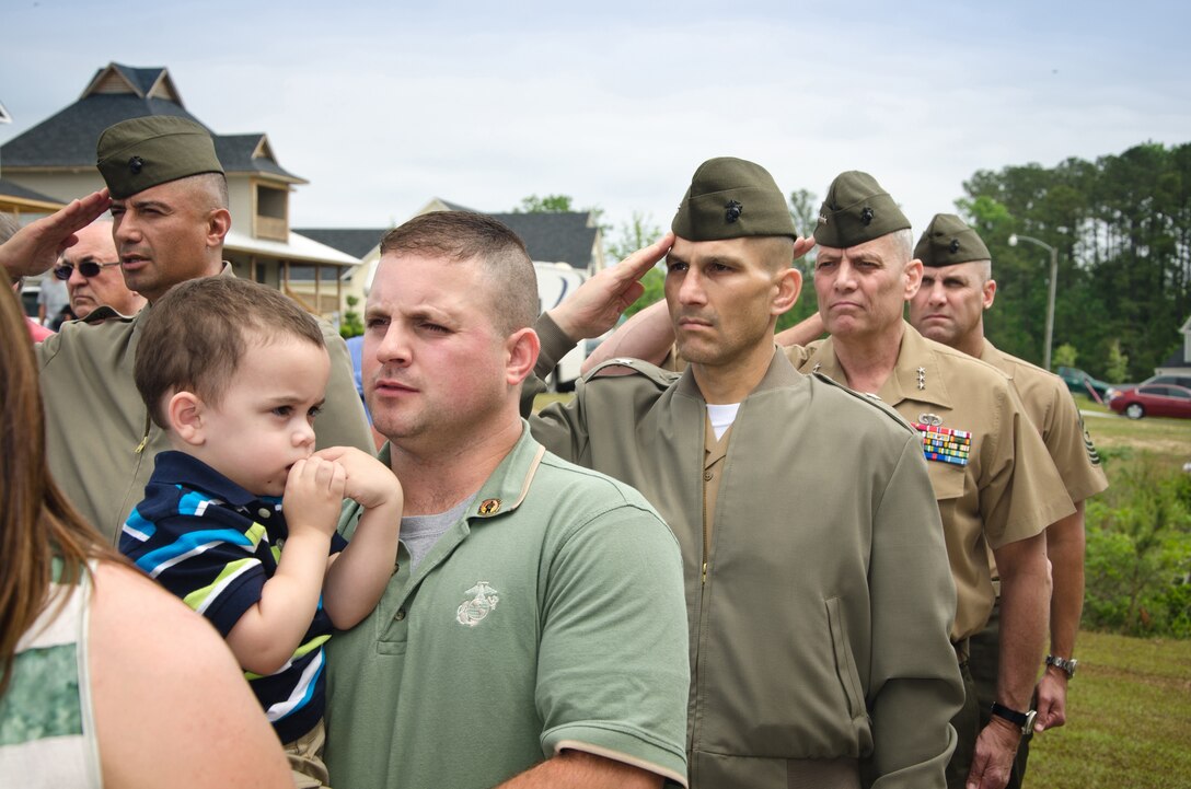 Retired Marine Staff Sergeant Vincent Gizzarelli holds his adopted son during the dedication ceremony of his family's brand new house, Jacksonville, N.C., Apr. 28. The house was built using supplies and donations from local businesses and various veterans' groups. Gizzarelli was medically retired from the Marine Corps after suffering traumatic brain injury and shrapnel wounds from multiple IED blasts that he sustained on his second tour to Iraq.