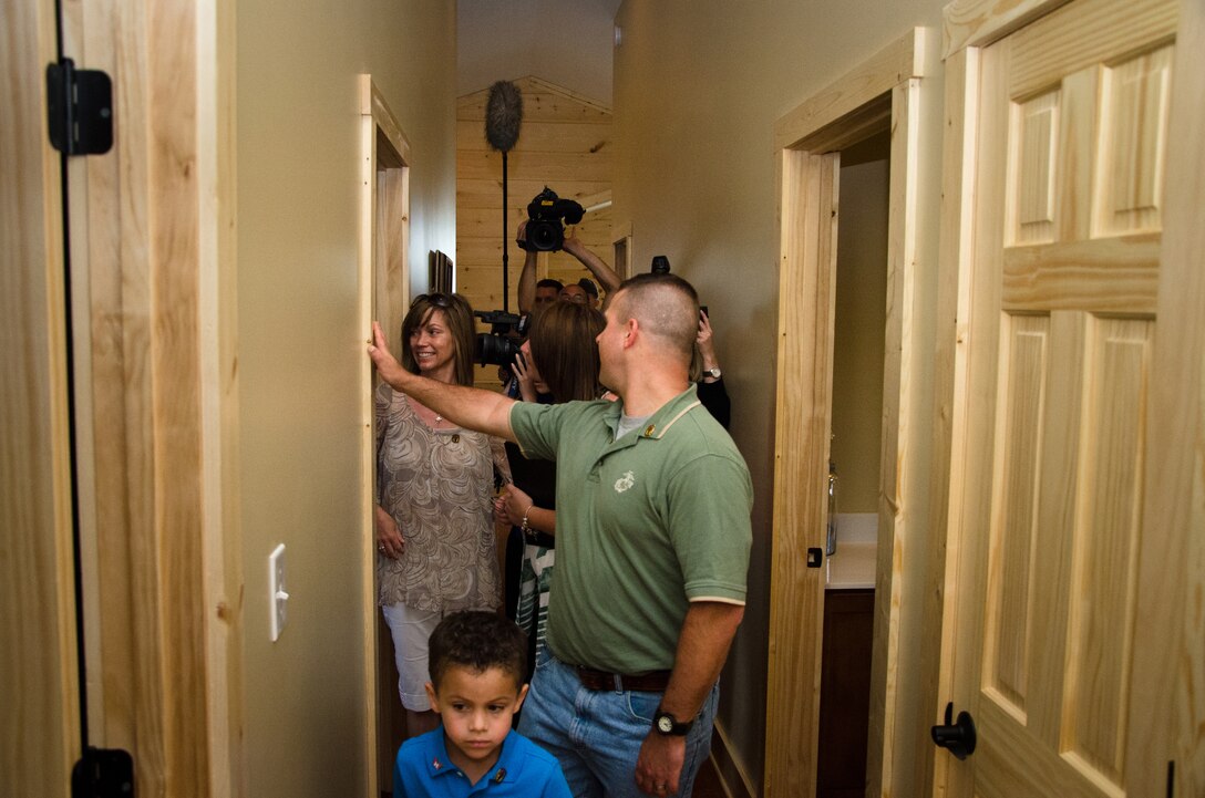 Retired Marine Staff Sergeant Vincent Gizzarelli is followed by television news reporters as he tours his house for the first time, Jacksonville, N.C., Apr. 28. The house was built using supplies and donations from local businesses and various veterans' groups. Gizzarelli was medically retired from the Marine Corps after suffering traumatic brain injury and shrapnel wounds from multiple IED blasts that he sustained on his second tour to Iraq.