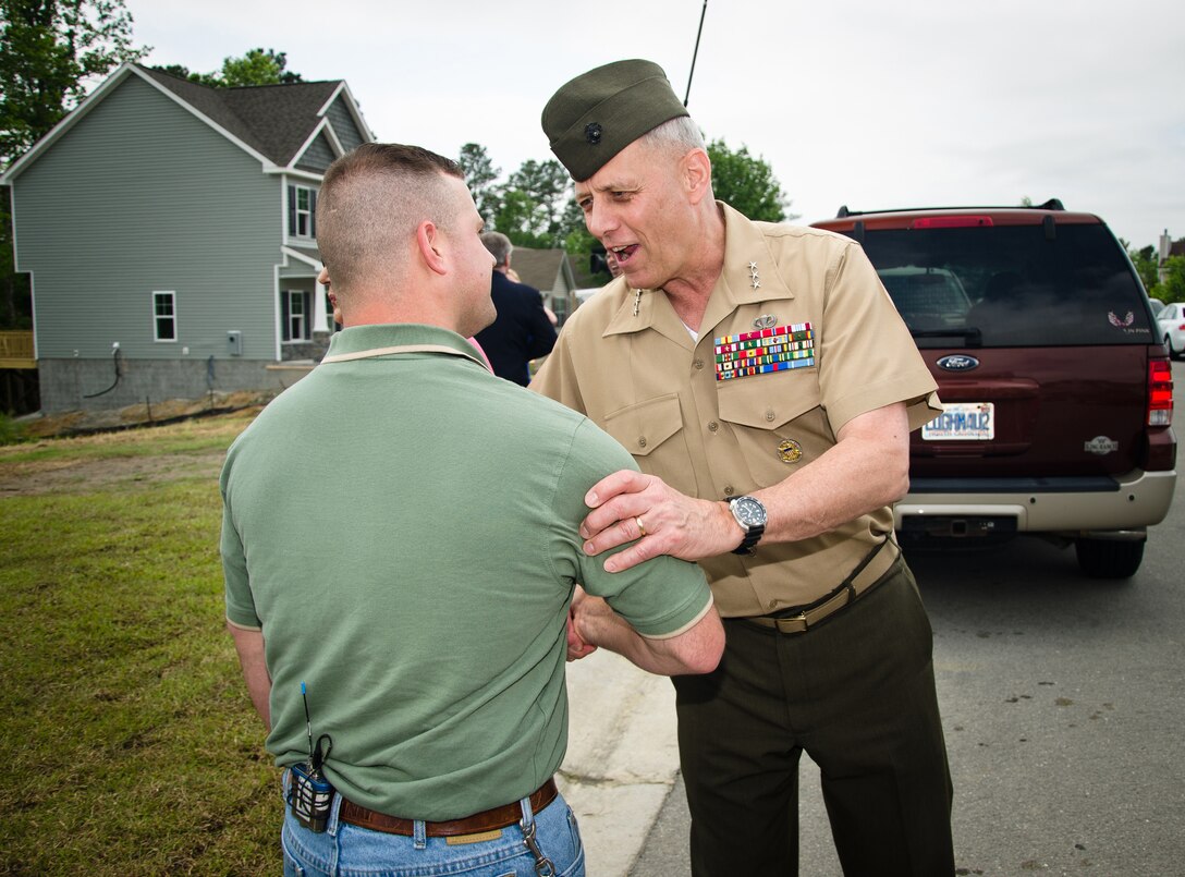 Retired Marine Staff Sergeant Vincent Gizzarelli shakes hands with Lt. Gen. John M. Paxton Jr., the commanding general of II Marine Expeditionary Force, after the dedication ceremony of his family's brand new house, Jacksonville, N.C., Apr. 28. The house was built using supplies and donations from local businesses and various veterans' groups. Gizzarelli was medically retired from the Marine Corps after suffering traumatic brain injury and shrapnel wounds from multiple IED blasts that he sustained on his second tour to Iraq.