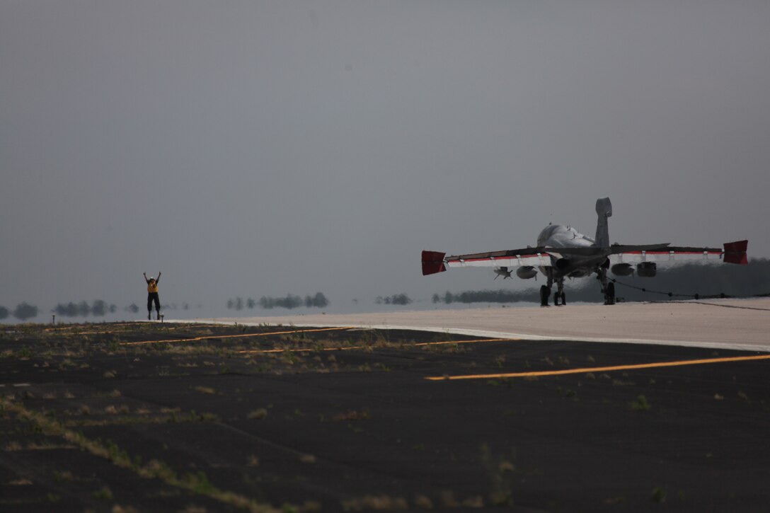 Sgt. Christopher D. Bentley, the maintenance chief for station recovery, directs an EA-6B Prowler pilot following an arrested landing aboard Marine Corps Air Station Cherry Point May 4 in preparation for the 2012 MCAS Cherry Point “Celebrate the Heritage” Air Show. The E28 Emergency Arresting Gear system is a cable system used to bring fast moving jets to a stop in the event of an emergency landing or need for a short landing space. For Marine Corps Air Station Cherry Point Station Recovery Marines their job and focus is to maintain and operate these systems on the flight line to save the lives of pilots and keep the aircraft safe. If a pilot, whose aircraft has a tail hook, i.e. EA-6B Prowler, needs to make an arrested landing for any emergency, station recovery comes out to the designated flight line gear where they prepare to catch the aircraft. Sgt. Christopher D. Bentley, the maintenance chief for station recovery said the design of these arrest points are to produce the same stopping abilities as the landing cable on an aircraft carrier and the operational procedures of these gears, takes a lot of dedication and time from the Station Recovery Marines. ::r::::n::They have to keep these gears well maintained, the gears use an engine to operate, and just like a car, they have a lot of moving parts that need continuous maintenance.