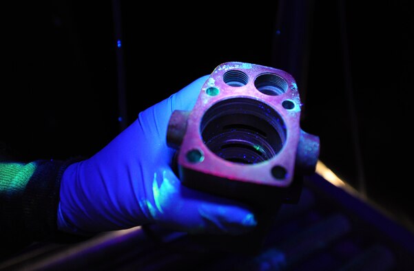 Tech. Sgt. Brian Gregory, 141st Maintenance Squadron non-destructive inspection technician, inspects a spoiler actuator that was previously dipped in a chemical that helps locate cracks under a black light in the inspection booth at the non-destructive inspection lab at Fairchild Air Force Base, Wash., April 26, 2012. Non-destructive inspection technicians also utilize x-ray equipment to look for water entrapment that could lead to corrosion. (U.S. Air Force photo by Airman 1st Class Taylor Curry)