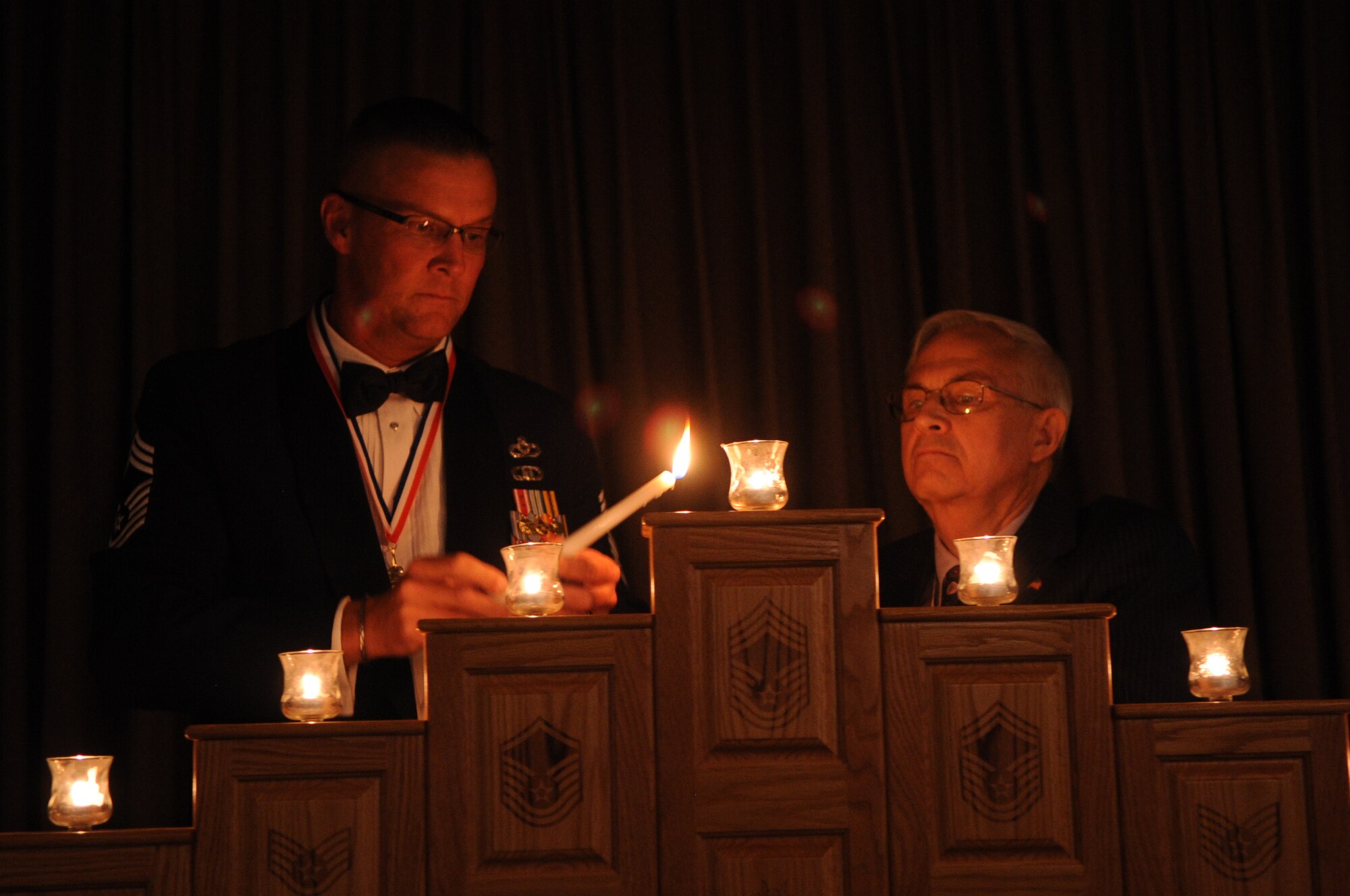 Chief Master Sgt. Christopher Crafton, 319th Civil Engineer Squadron, and Jim Bradshaw, honorary ambassador to Grand Forks Air Force Base, N.D., light the final candle during the Chief’s Recognition Ceremony on April 27, 2012. (U.S. Air Force photo by Staff Sgt. Amanda N. Grabiec)