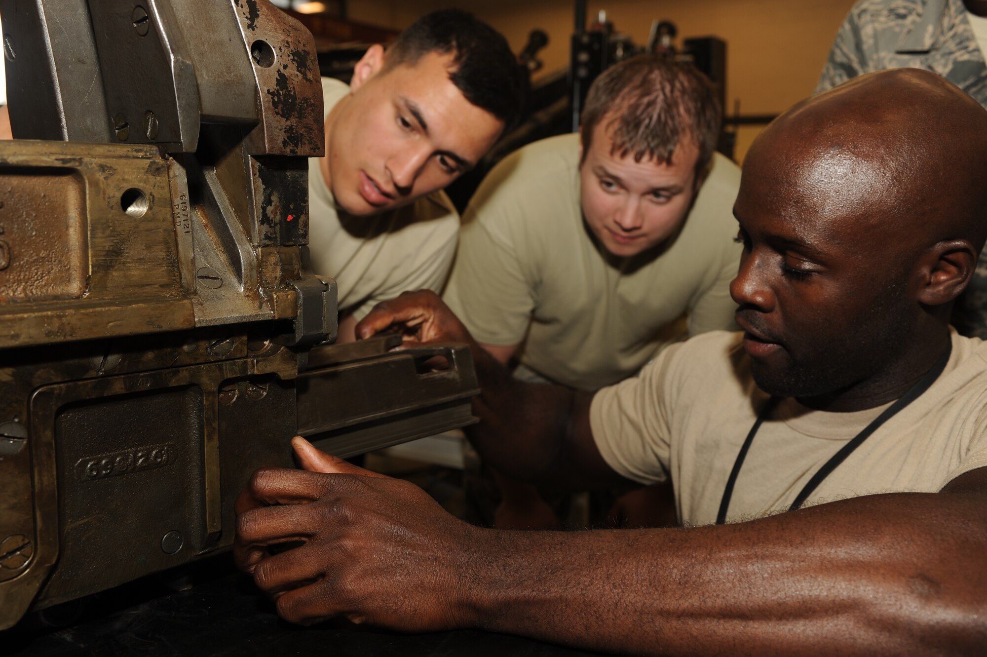 U.S. Air Force Tech. Sgt. Robin Clements, 27th Special Operations Maintenance Squadron, shows Airman Jordan Gonzales and Staff Sgt. Ryan Dempsey how to properly disassemble the 40 mm weapon loader in a maintenance facility at Cannon Air Force Base, N.M., May 2, 2012. The 40mm weapon is used on the AC-130H Spectre gunship. (U.S Air Force photo by Airman 1st Class Eboni Reece)