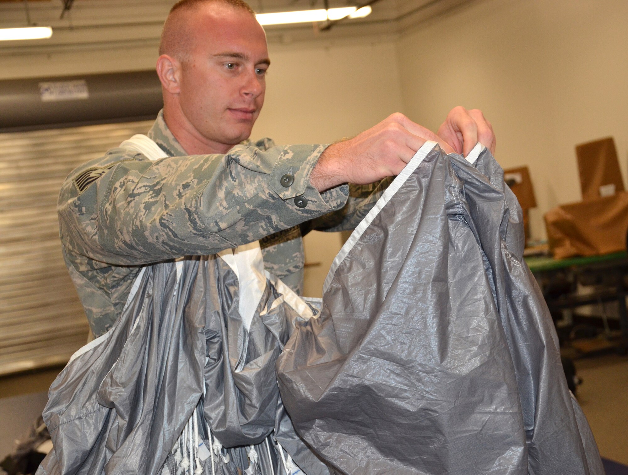 Tech Sgt. Christopher Schwan, 920th Rescue Wing, Patrick Air Force Base, Fla., Aircrew Flight Equipment Specialist reservist, folds up a parachute used by combat search and rescue operators here. Schwan was honored as the Recruit Fire Fighter of the Year for Brevard County. He was chosen out of 70 recruits for 2012. As a fire fighter, Schwan uses the same inspiration he uses here, saving lives. "I love both of my jobs, they both give me the opportunity to save a life," said Schwan. (U.S. Air Force photo/2nd Lt. Leslie Forshaw)