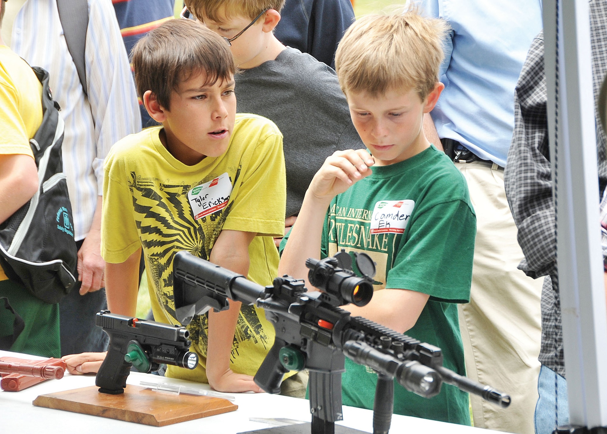 KIRTLAND AFB, N.M. -- Fifth-graders Tyler Erickson, left, from Seven Bar Elementary and Camden Ek, right, from Rio Rancho Elementary, check out weaponry from Sandia National  Labs at one of several displays. (Photo by Todd Berenger)