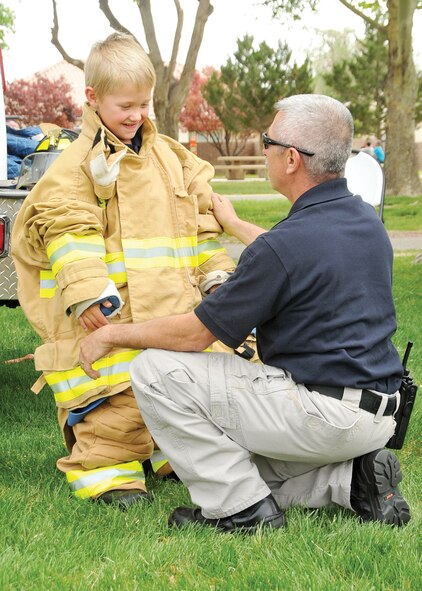 KIRTLAND AFB, N.M. -- Five-year-old Brennan Nelson suits up in firefighter gear with the help of Robert Sanchez of the Sandia National Labs Emergency Response Team. (Photo by Todd Berenger)