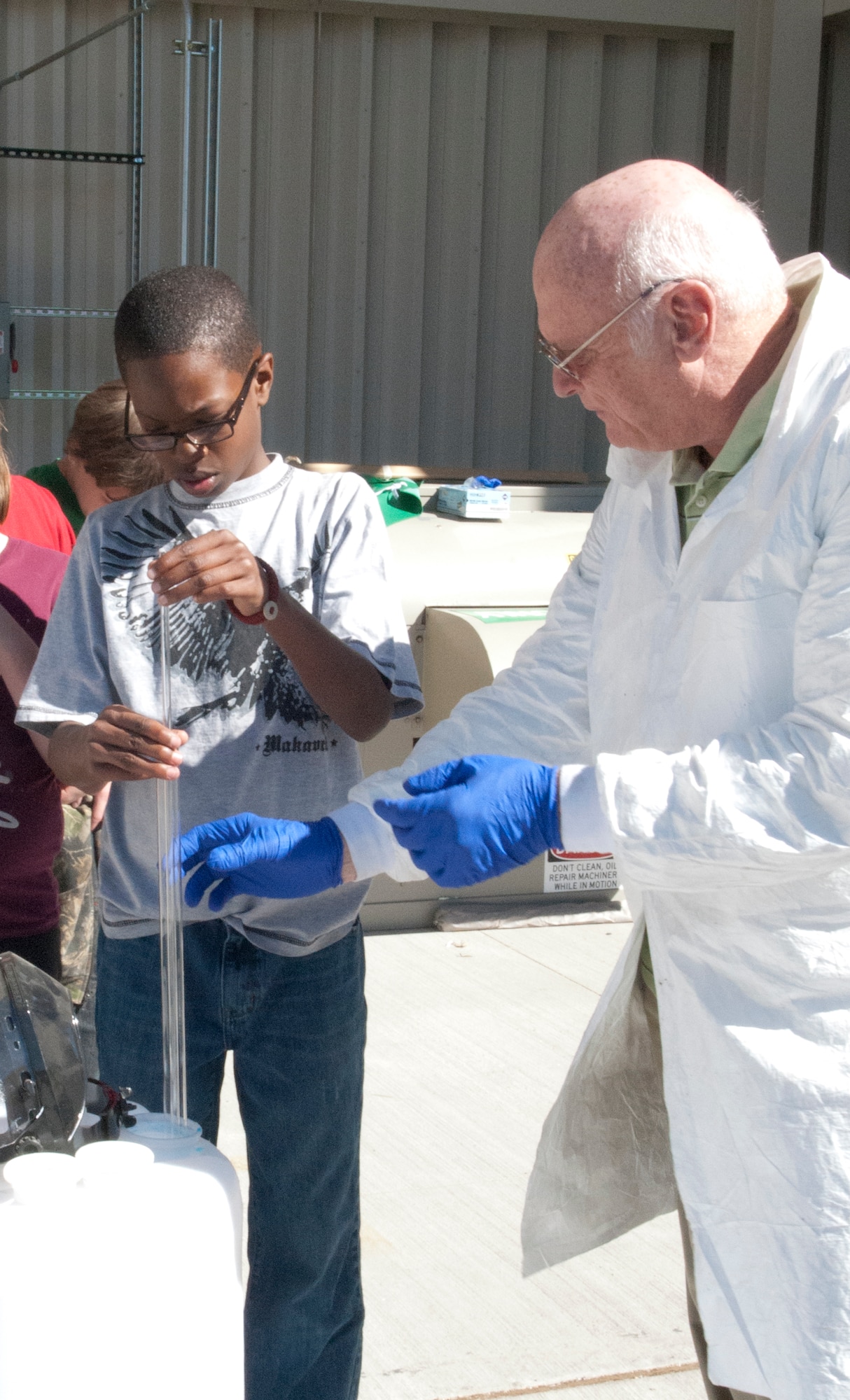 Bill Goings, 90th Civil Engineer Squadron hazardous waste program manager, shows Omari Stewart, Freedom Elementary School sixth-grade student and son of Staff Sgt. Frederick Stewart, 90th Force Support Squadron shift leader, how to use a composite liquid waste sampler at the Warren recycling center April 23. A COLIWASA is a device that utilizes air pressure to take samples of liquid substances, and hazardous waste handlers use them to obtain samples of unknown substances for testing. (U.S. Air Force photo by Airman Jason Wiese)