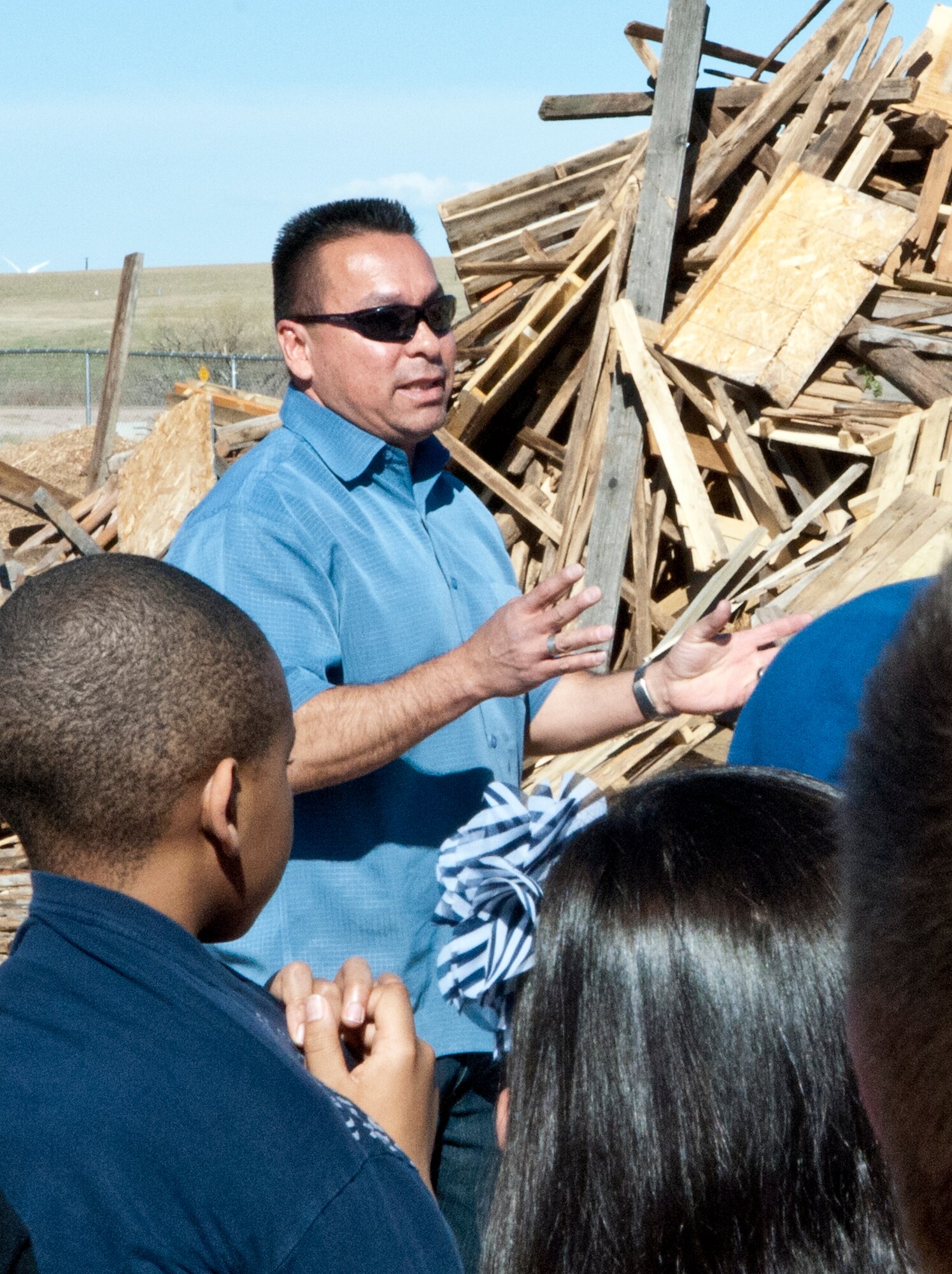 Ernie Cisneros, 90th Civil Engineer Squadron grounds quality assurance personnel, tells Freedom Elementary School students about F. E. Warren’s composting endeavor at the base compost facility April 23. The pile of pallets that he stands in front of are slated to be ground into wood chips to be used as landscaping mulch. (U.S. Air Force photo by Airman Jason Wiese)