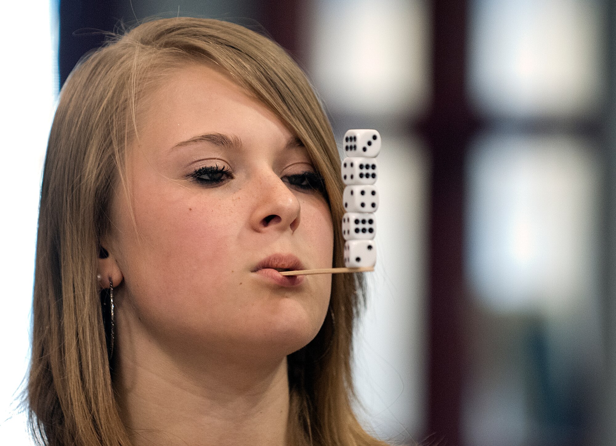 Katleyn Waldo, 13, balances a stack of five dice on a stick in a game at the Month of the Military Child festivities at the F. E. Warren Air Force Base Youth Center April 27. Waldo, the daughter of Senior Master Sgt. Robert Waldo, 90th Munitions Squadron, was a volunteer at the event helping at this game table and painting faces. (U.S. Air Force photo by R.J. Oriez)